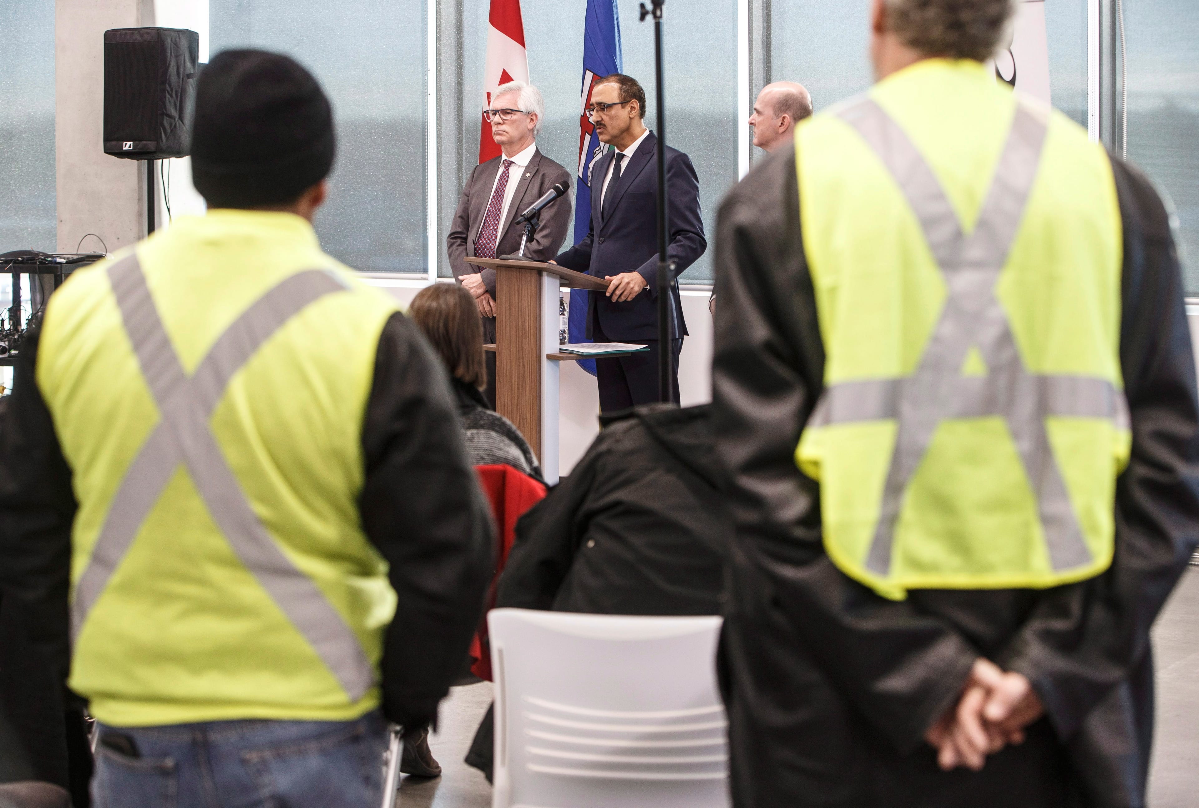 Concerned oil field workers watch as Canada's Minister of International Trade Diversification Jim Carr, left, Canada's Minister of Natural Resources Amarjeet Sohi, centre and Randy Boissonnault, Edmonton M.P. speak during press conference to announce support for Canada's oil and gas sector, in Edmonton on Tuesday, Dec. 18, 2018. THE CANADIAN PRESS/Jason Franson