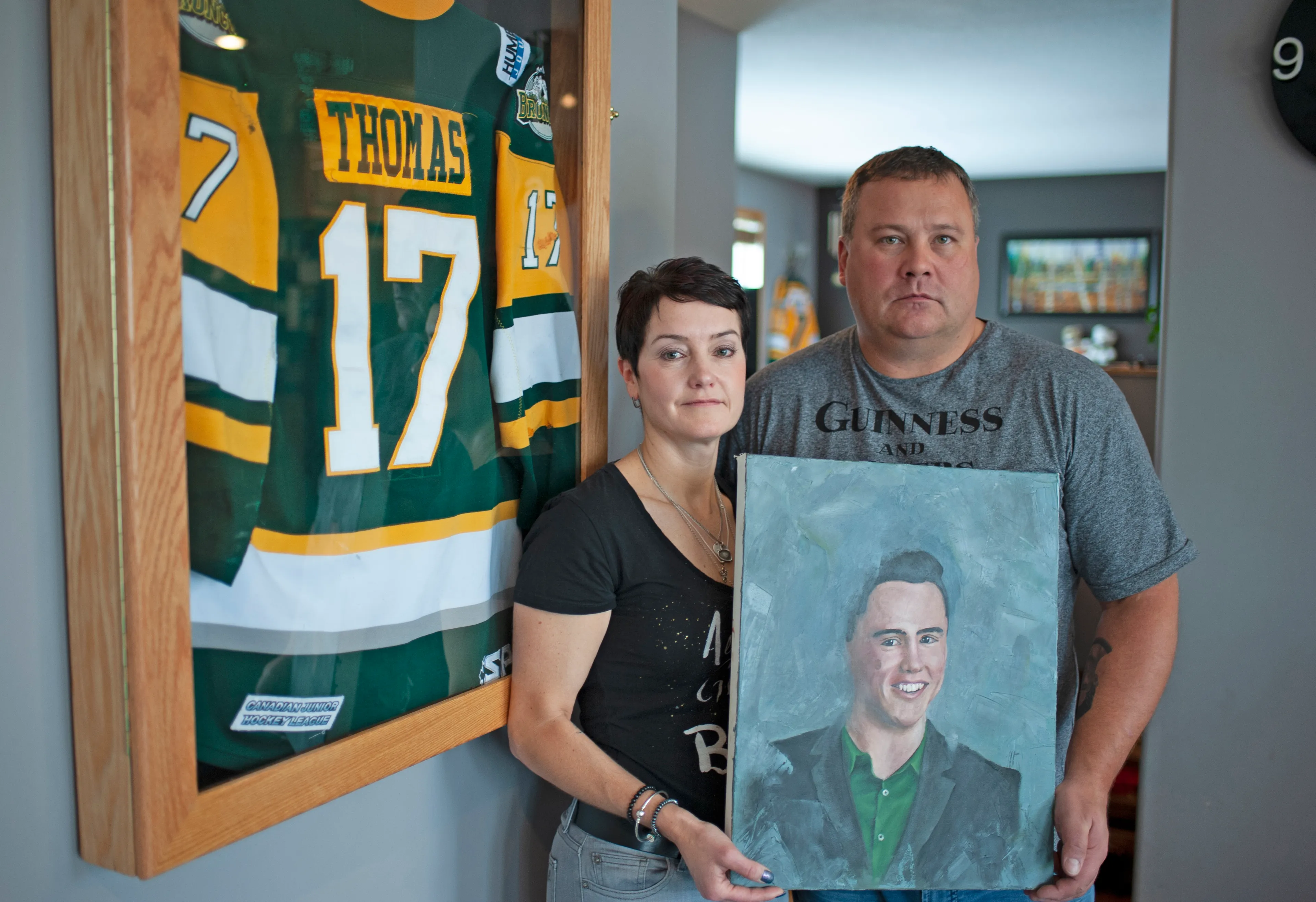 Laurie and Scott Thomas pose with a painting of their late son, Evan, in their Saskatoon home. (Photograph by Mark Taylor)