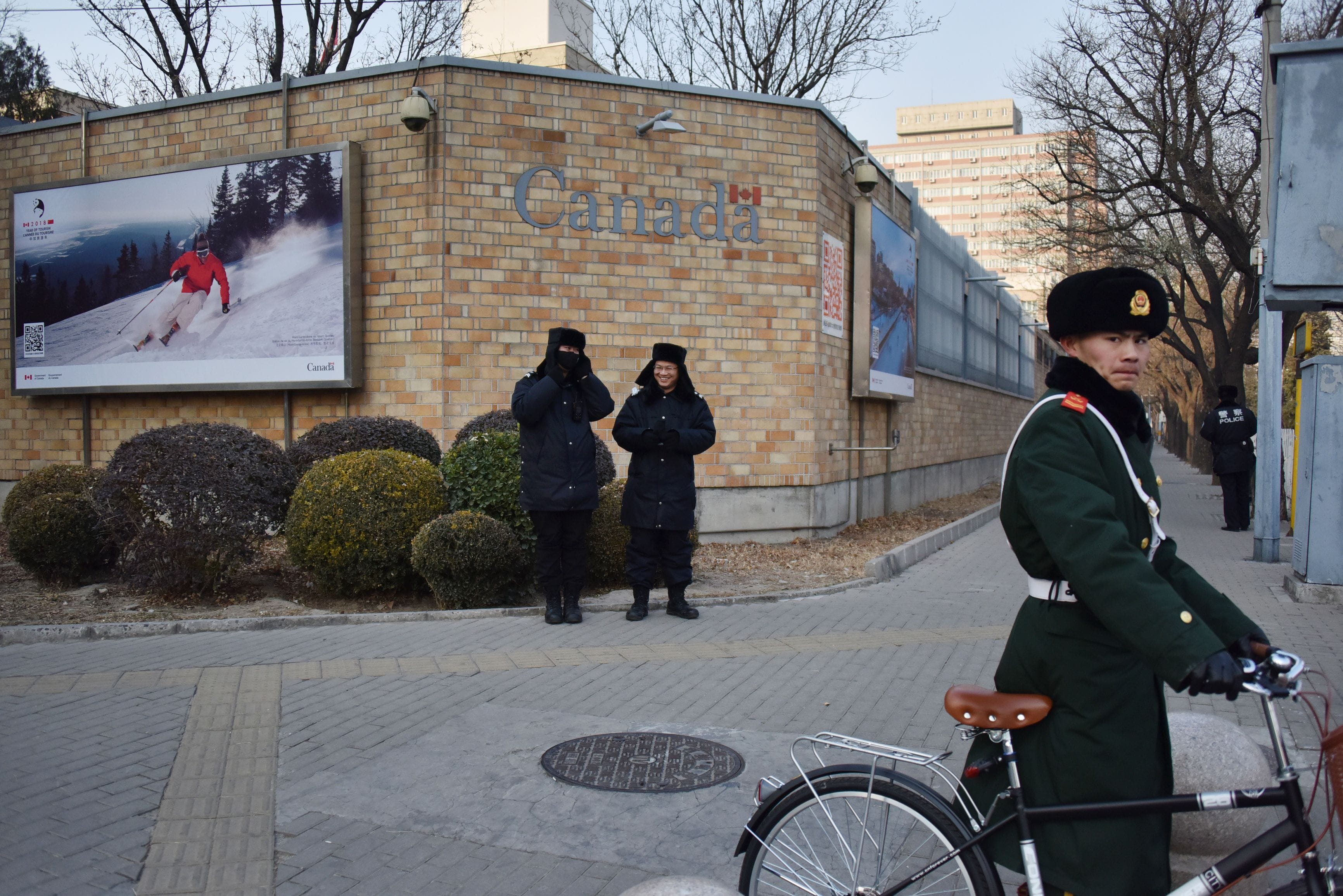 Chinese police officers stand guard outside the Canadian embassy in Beijing, as a paramilitary police officer walks his bicycle on Dec. 10, 2018. (GREG BAKER/AFP/Getty Images)