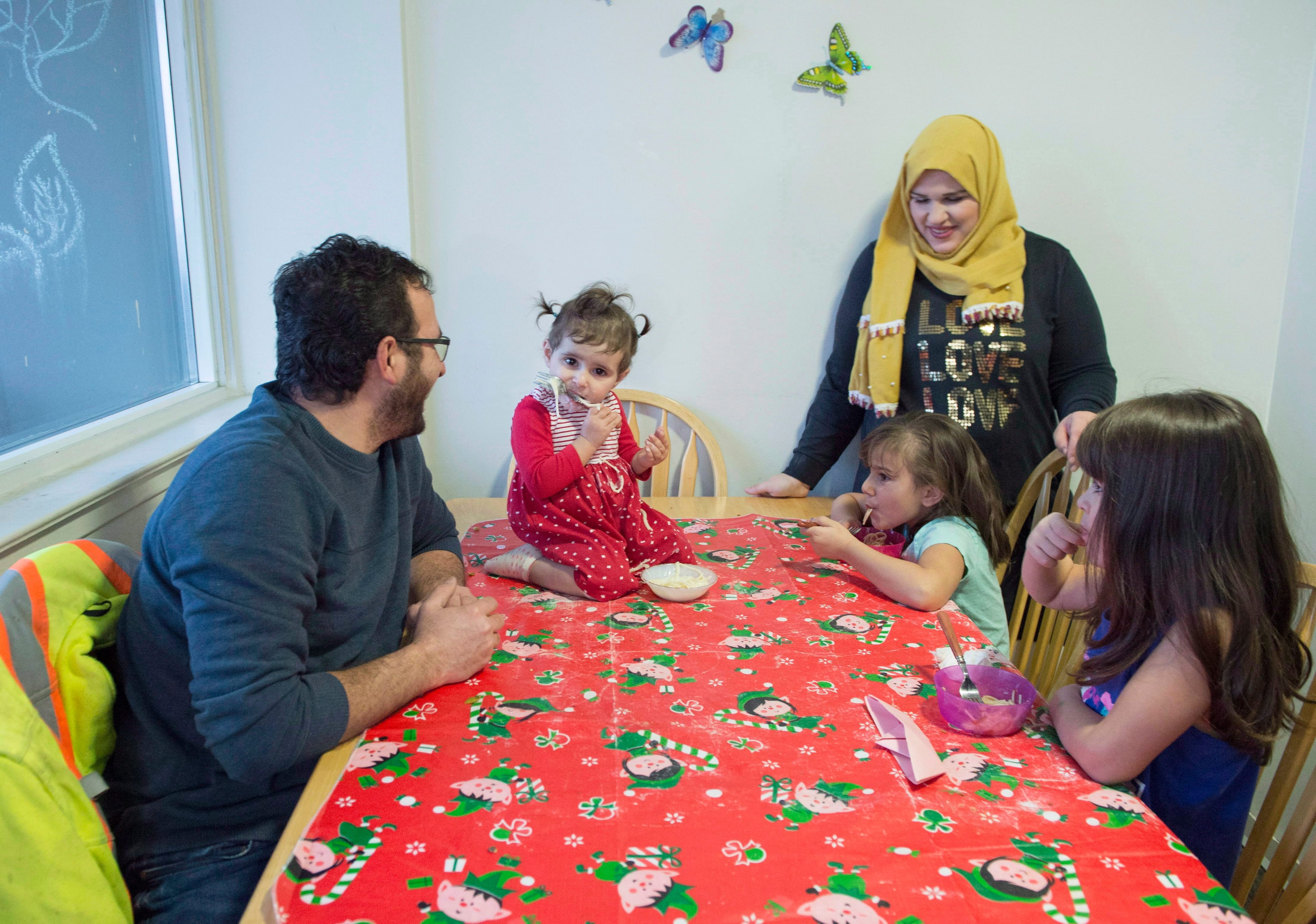 Syrian refugee family Mohammad Al Mnajer and wife Fouzia Al Hashish sit with their three daughters Judy, second left, Jaidaa, far right, and Baylasan as they eat their after school snack at their home in Mississauga, Ont., Thursday, Dec. 13, 2018. THE CANADIAN PRESS/Frank Gunn