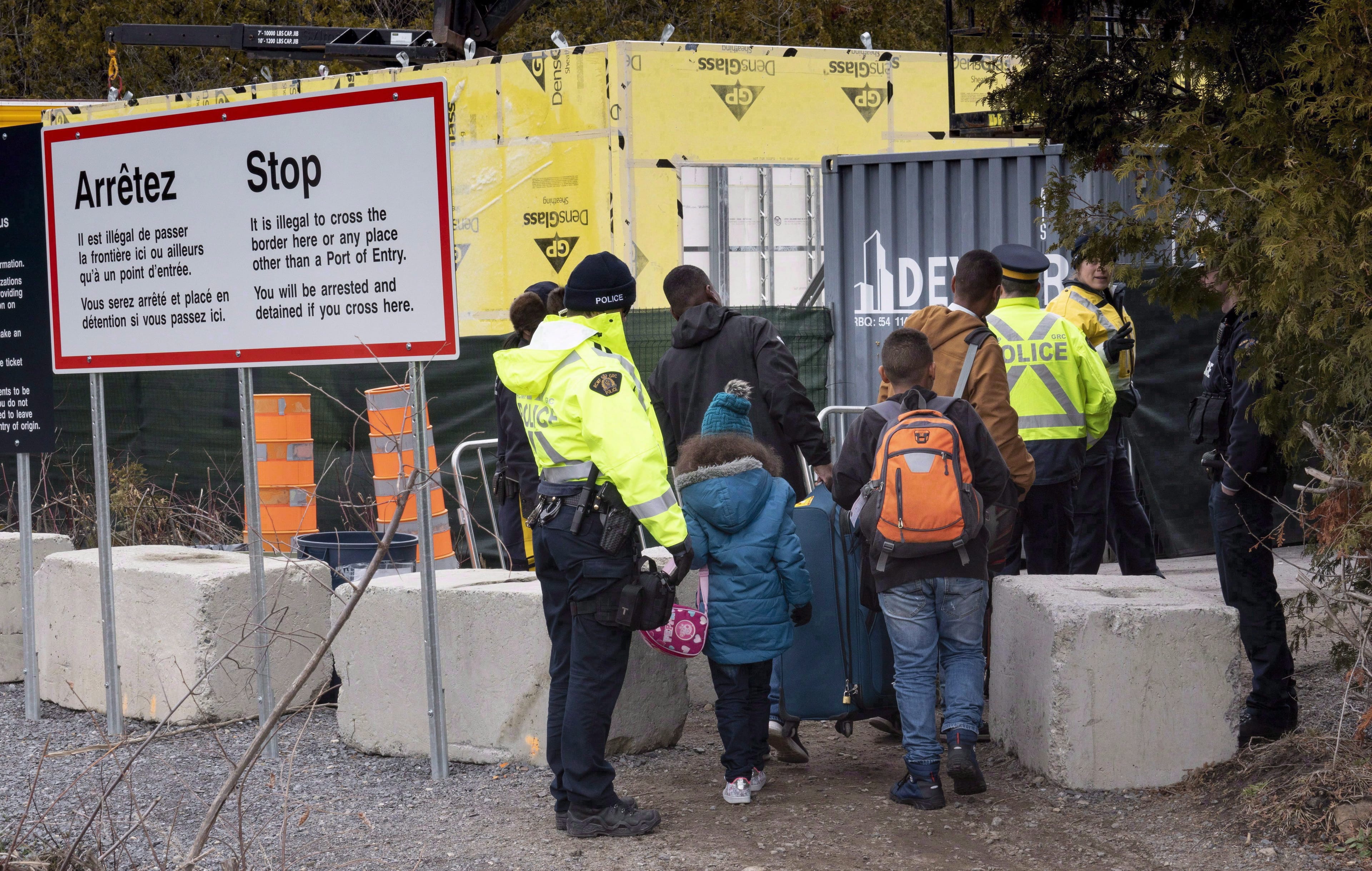 A family, claiming to be from Columbia, is arrested by RCMP officers as they cross the border into Canada from the United States as asylum seekers on April 18, 2018 near Champlain, NY. (THE CANADIAN PRESS/Paul Chiasson)