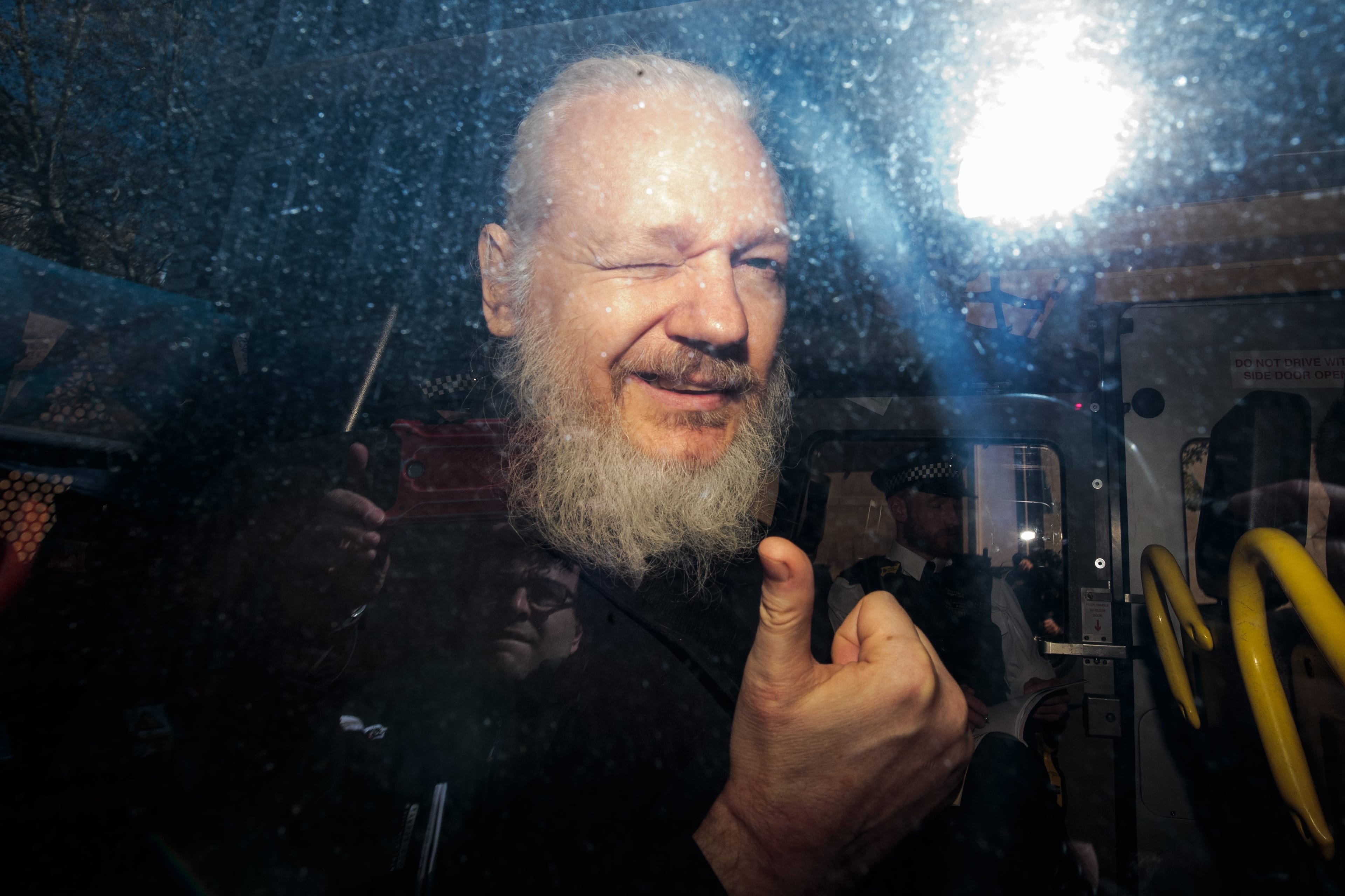 Assange gestures to the media from a police vehicle on his arrival at Westminster Magistrates court on April 11, 2019 in London, England. (Jack Taylor/Getty Images)