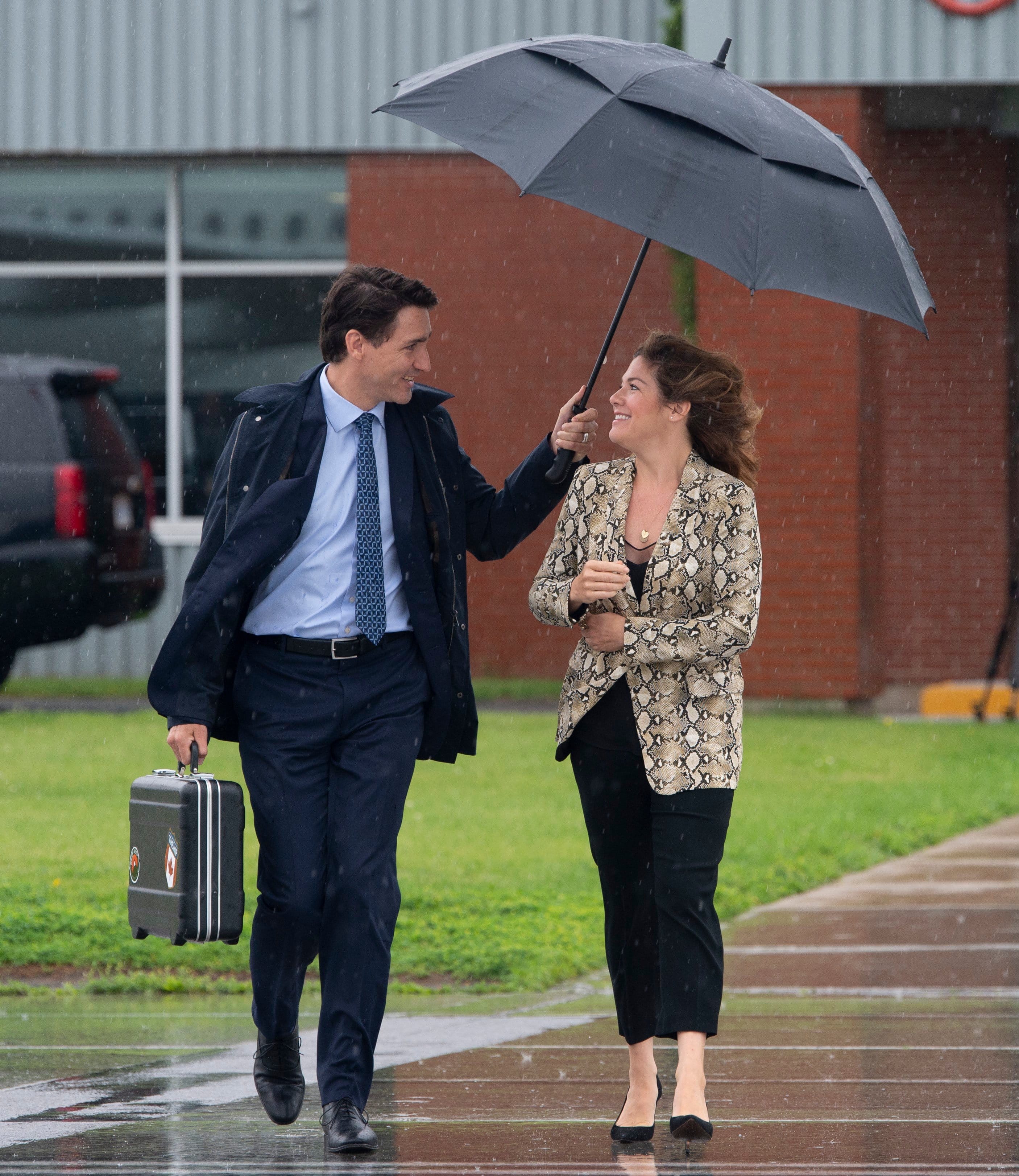 Canadian Prime Minister Justin Trudeau holds the umbrella over his wife Sophie Gregoire Trudeau as they make their way to board the government plane as they depart for the G20 in Japan, on Wednesday June 26, 2019 in Ottawa. (Adrian Wyld/CP)