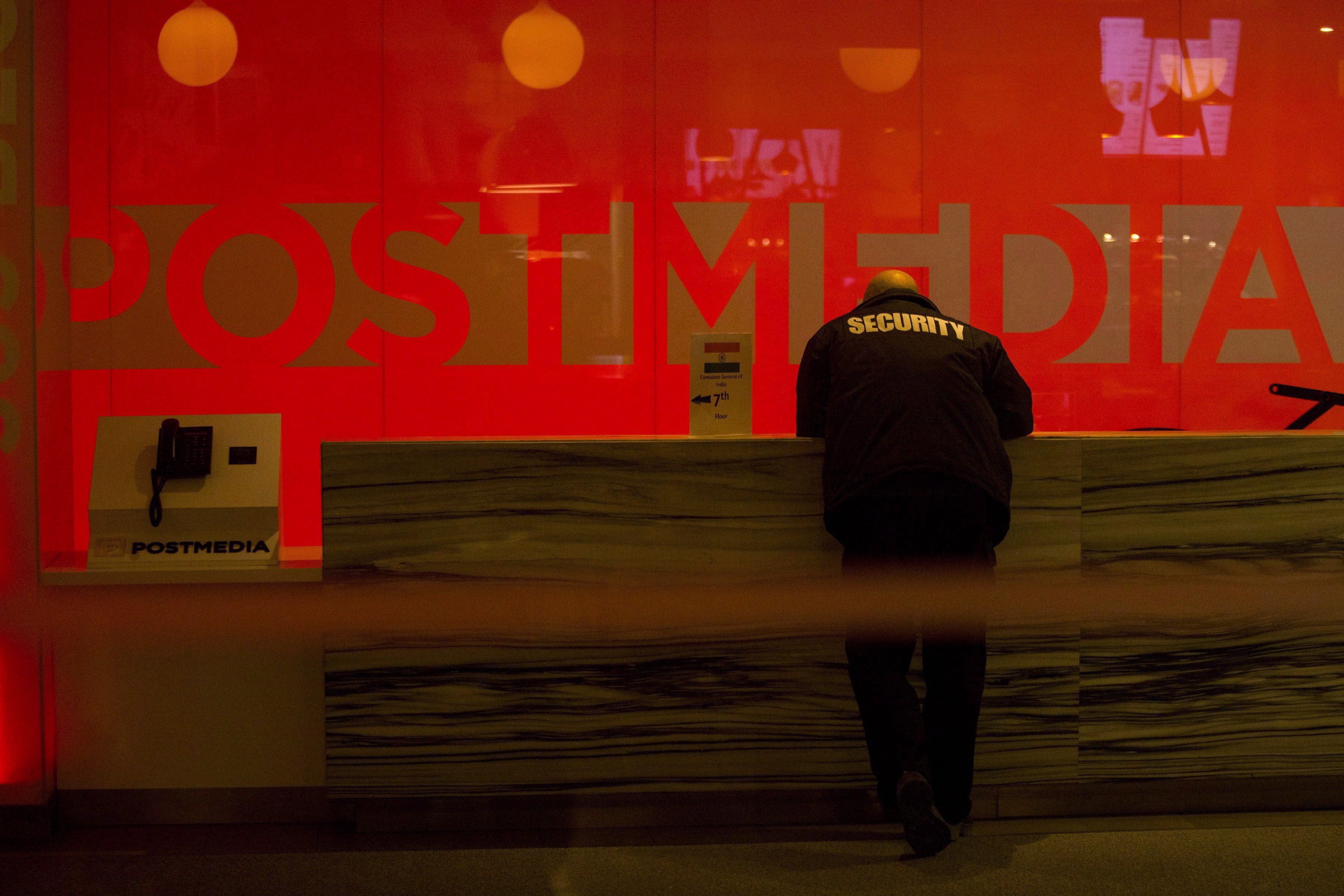 A security guard stands by the front reception desk at Postmedia's Toronto headquarters on Monday, March 12, 2018 (THE CANADIAN PRESS/Chris Young)