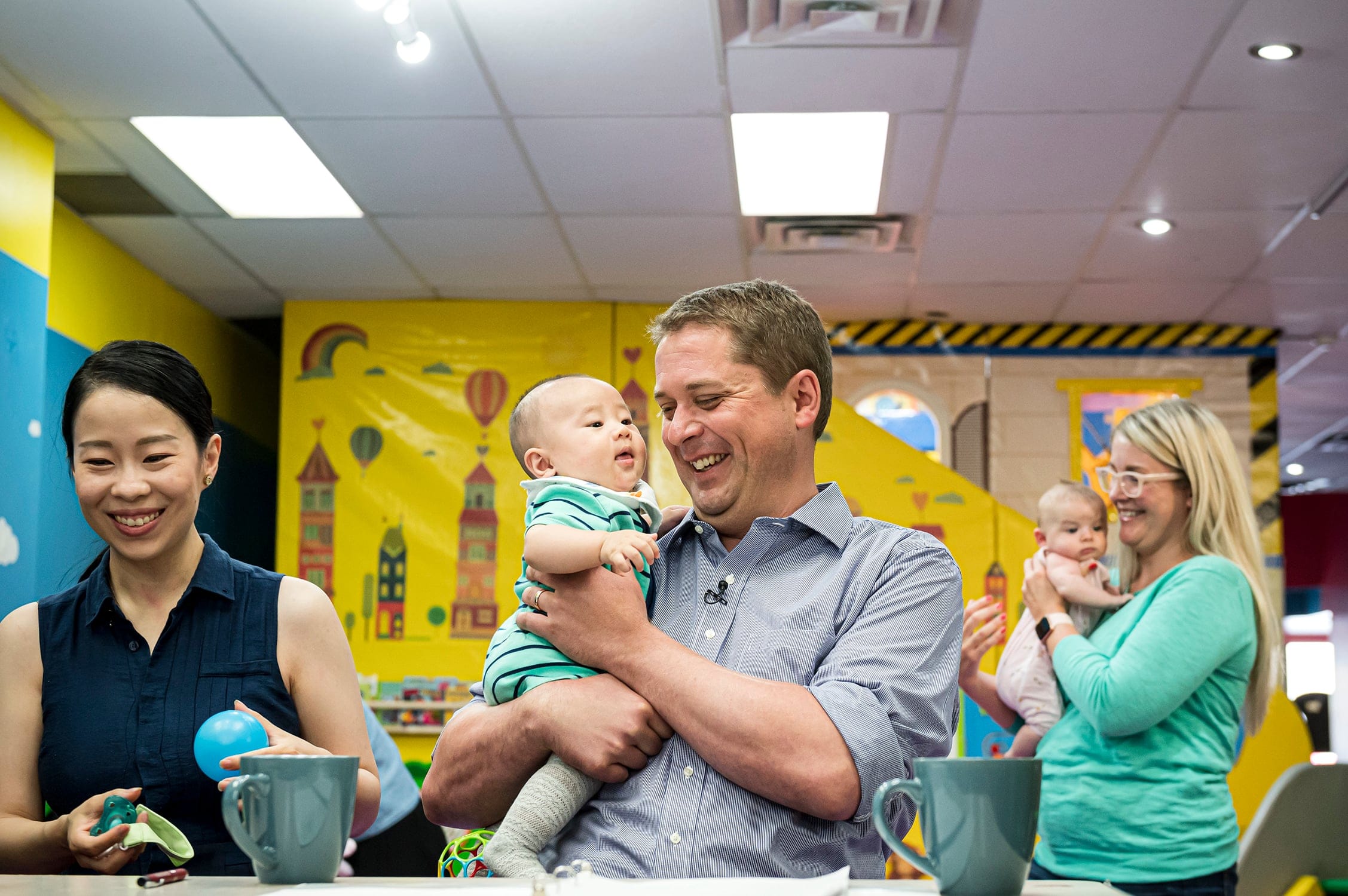 Federal Conservative leader Andrew Scheer holds a 4-month old at a child care facility (Christopher Katsarov/CP)