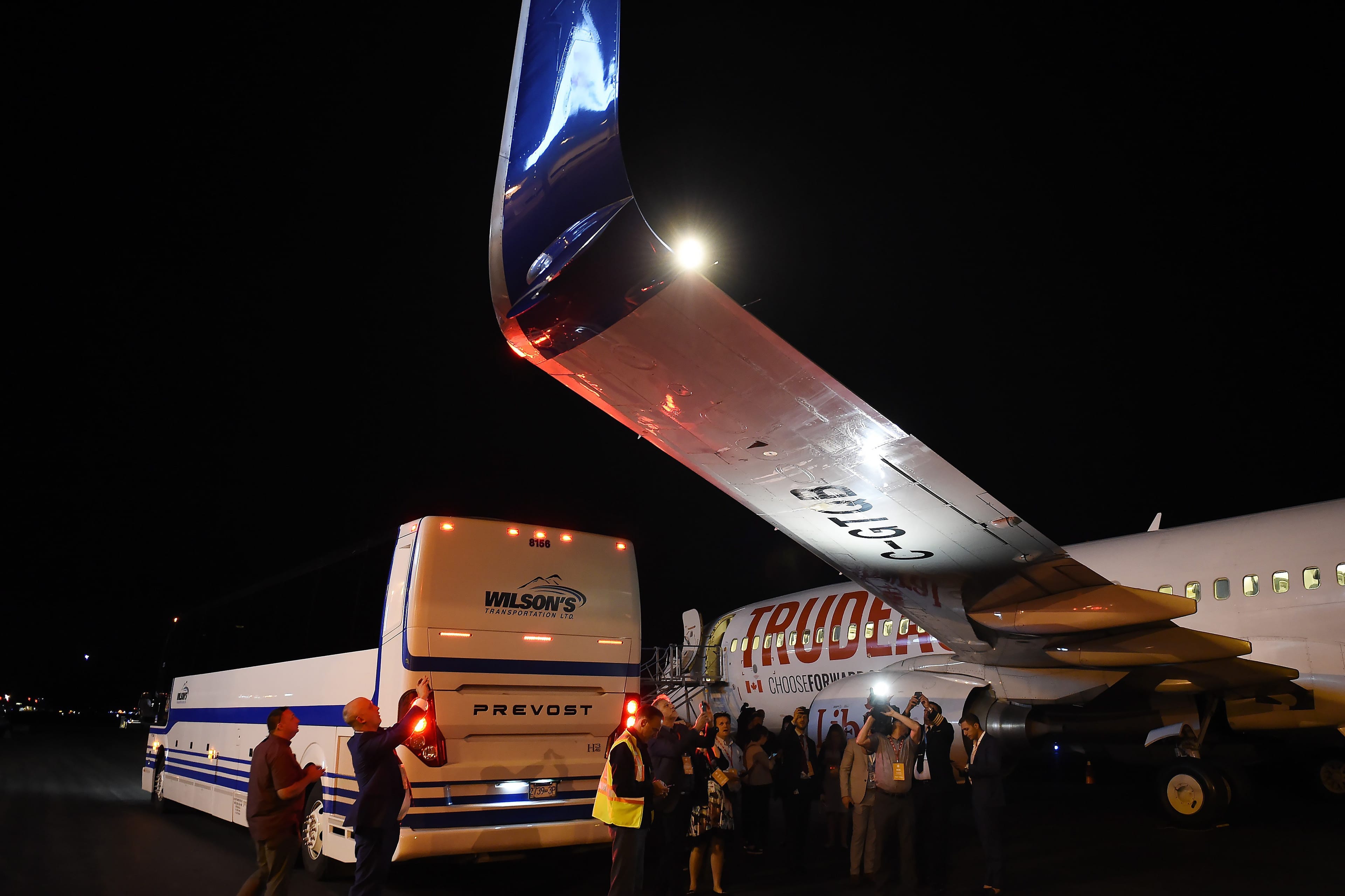 Members of the media inspect the wing from Liberal Leader Justin Trudeau's campaign plane after it was struck by the press bus. (Sean Kilpatrick/CP)