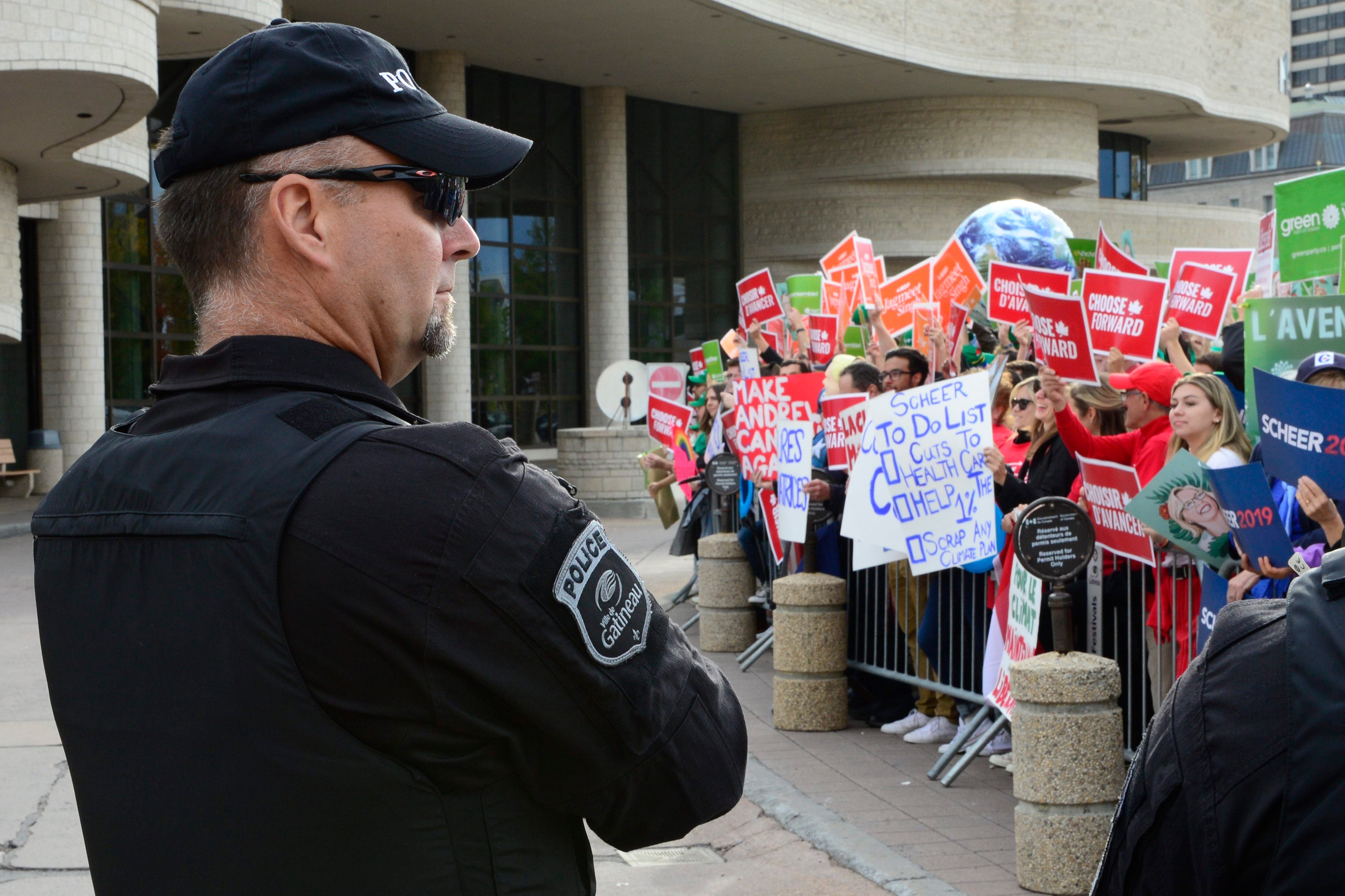 Party supporters hold up signs outside the federal election leaders debate in Gatineau, Que., on Oct. 7, 2019 (Frank Gunn/CP)