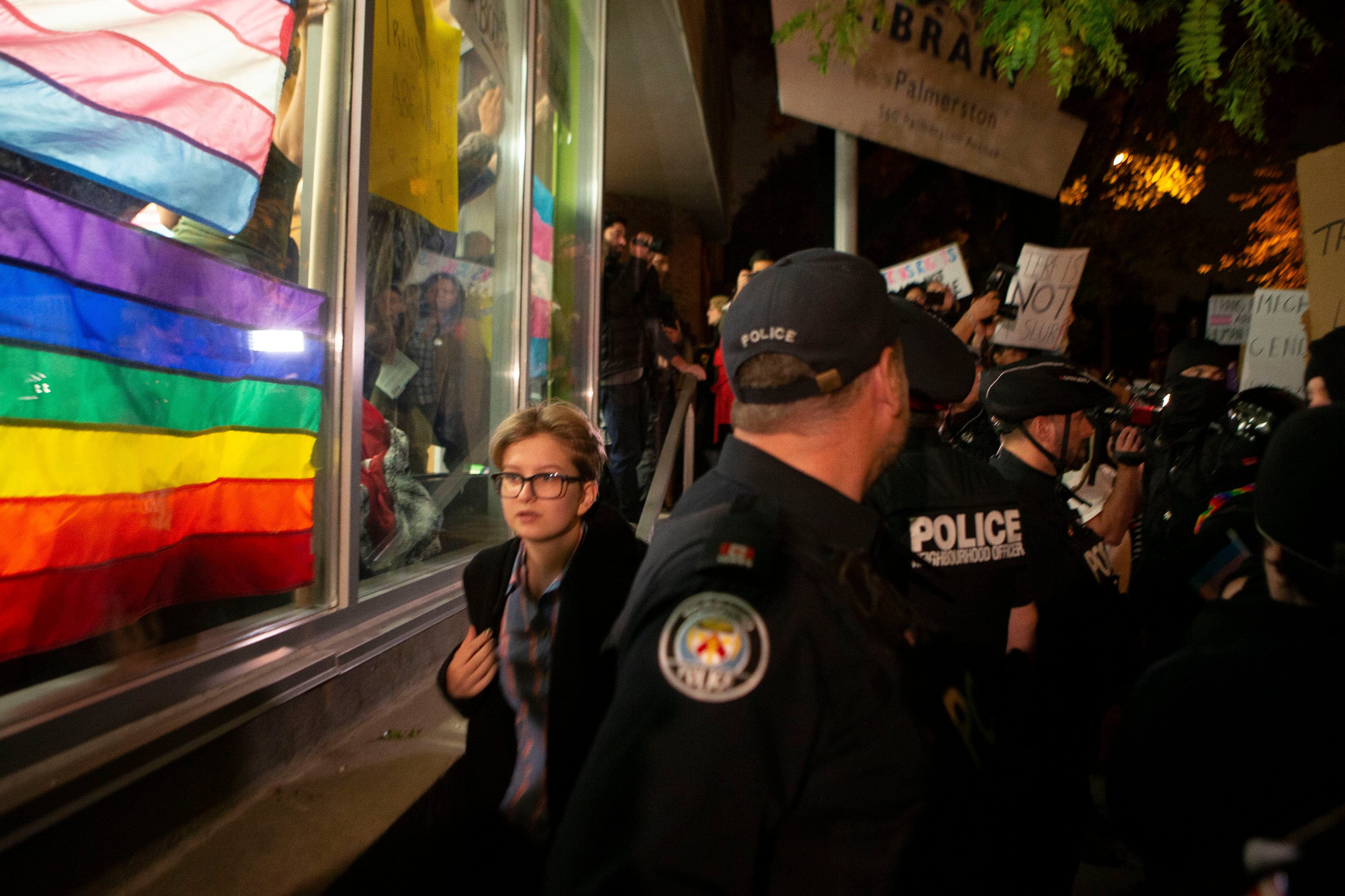 An audience member departs behind a line of police as pro-transgender rights activists gather outside a Toronto library after writer Meghan Murphy spoke at an event on Tuesday. (Chris Young/CP)