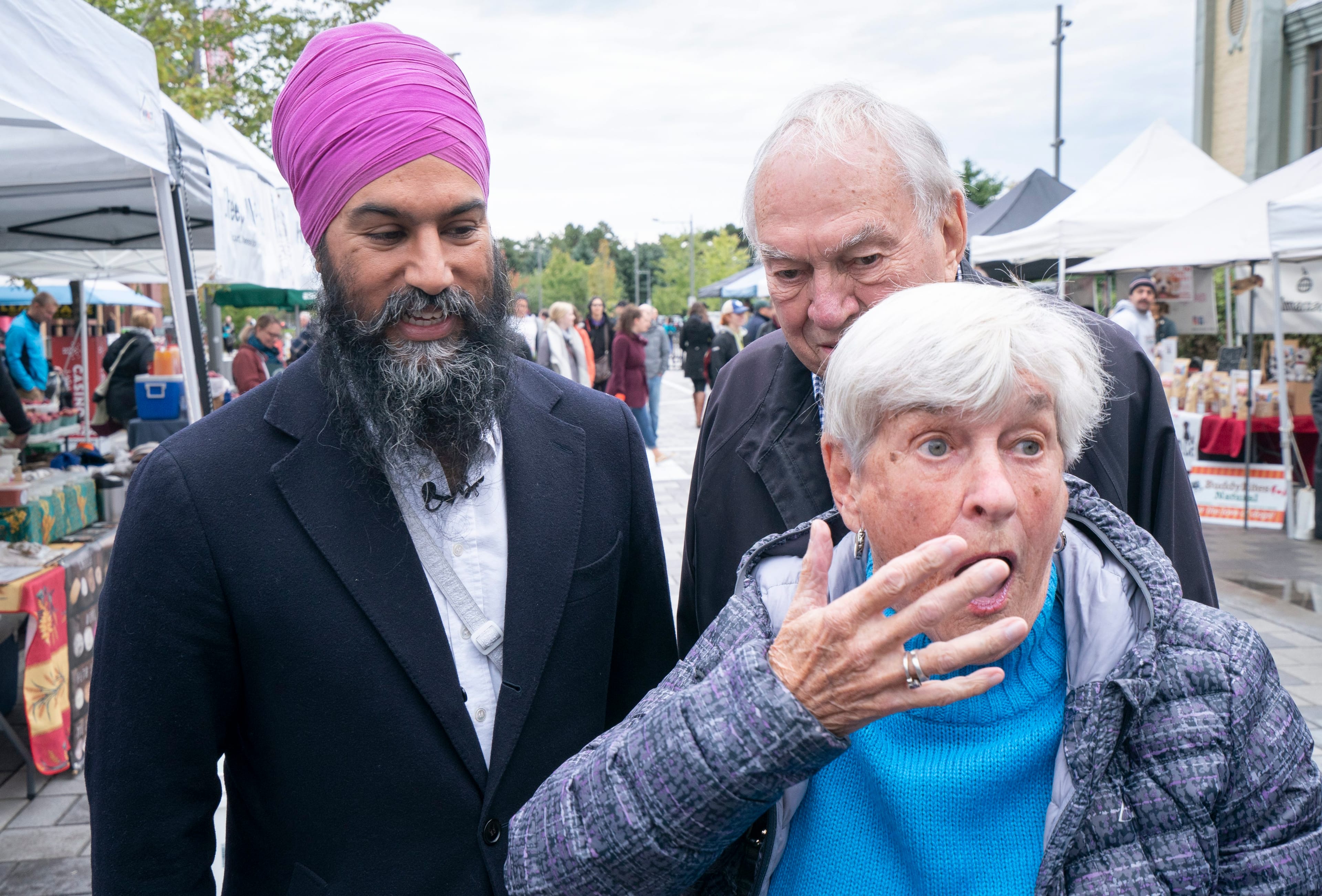 A woman reacts after turning around and seeing the assembled media after meeting with NDP Leader Jagmeet Singh and former leader Ed Broadbent at a farmers market in Ottawa (Paul Chiasson/CP)