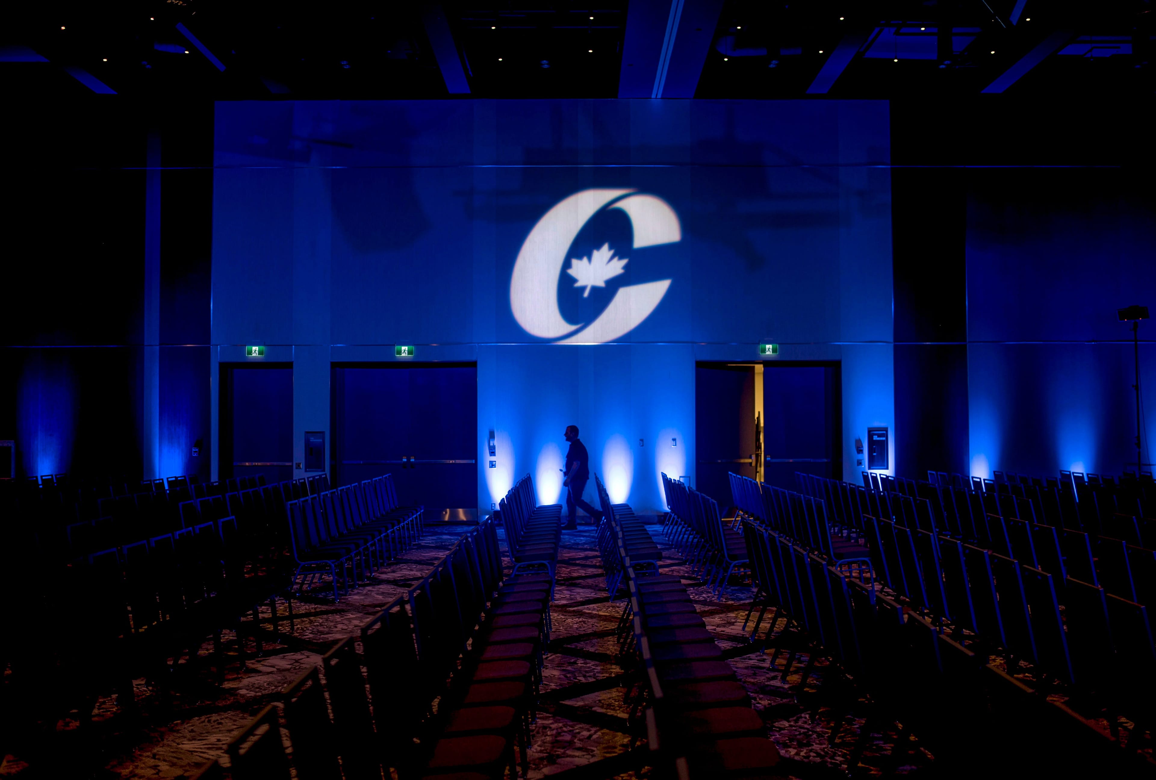 A man is silhouetted walking past a Conservative Party logo before the opening of the Party's national convention in Halifax on Aug. 23, 2018. (CP/Darren Calabrese)