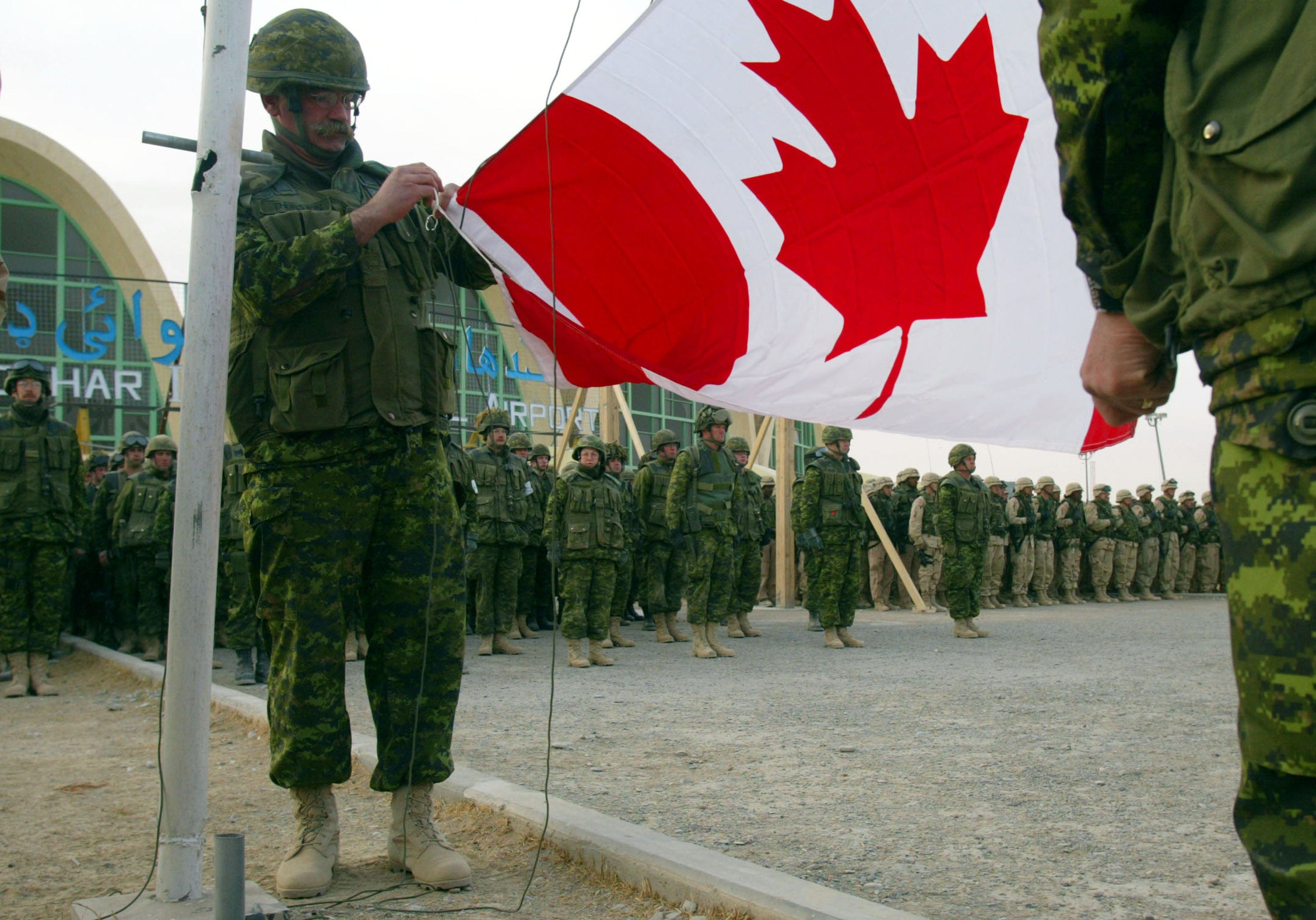 Canadian soldiers unfurl the Canadian flag for the first time at the Kandahar Airbase in Afghanistan on Feb. 11, 2002 (Joe Raedle/Getty Images)