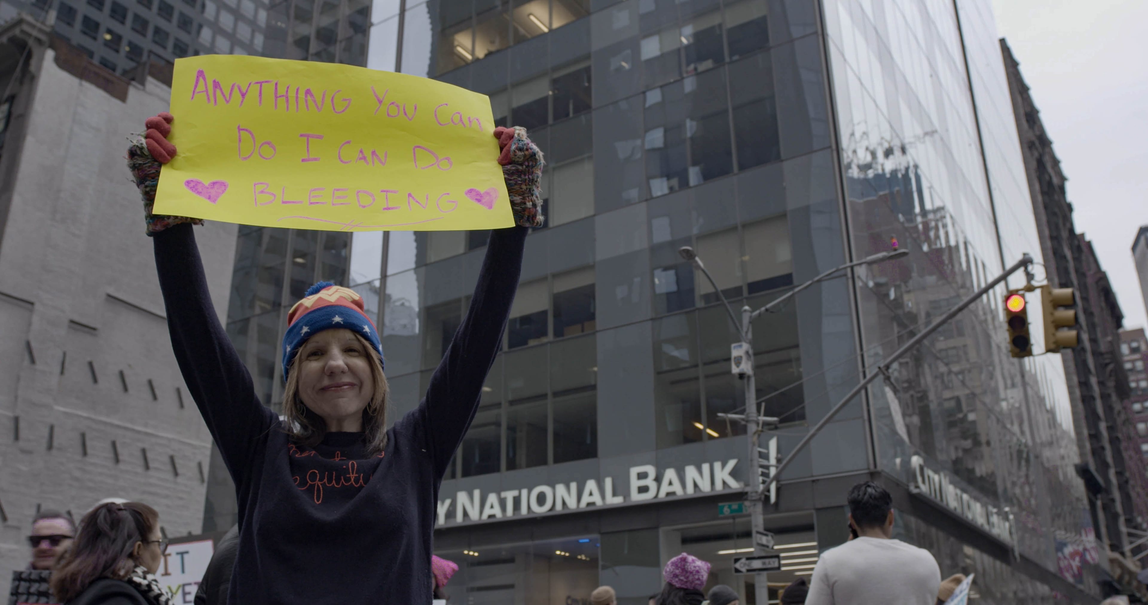 A woman holding up a sign at the New York City women's in Mar. 2019. (From the film Pandora's Box)