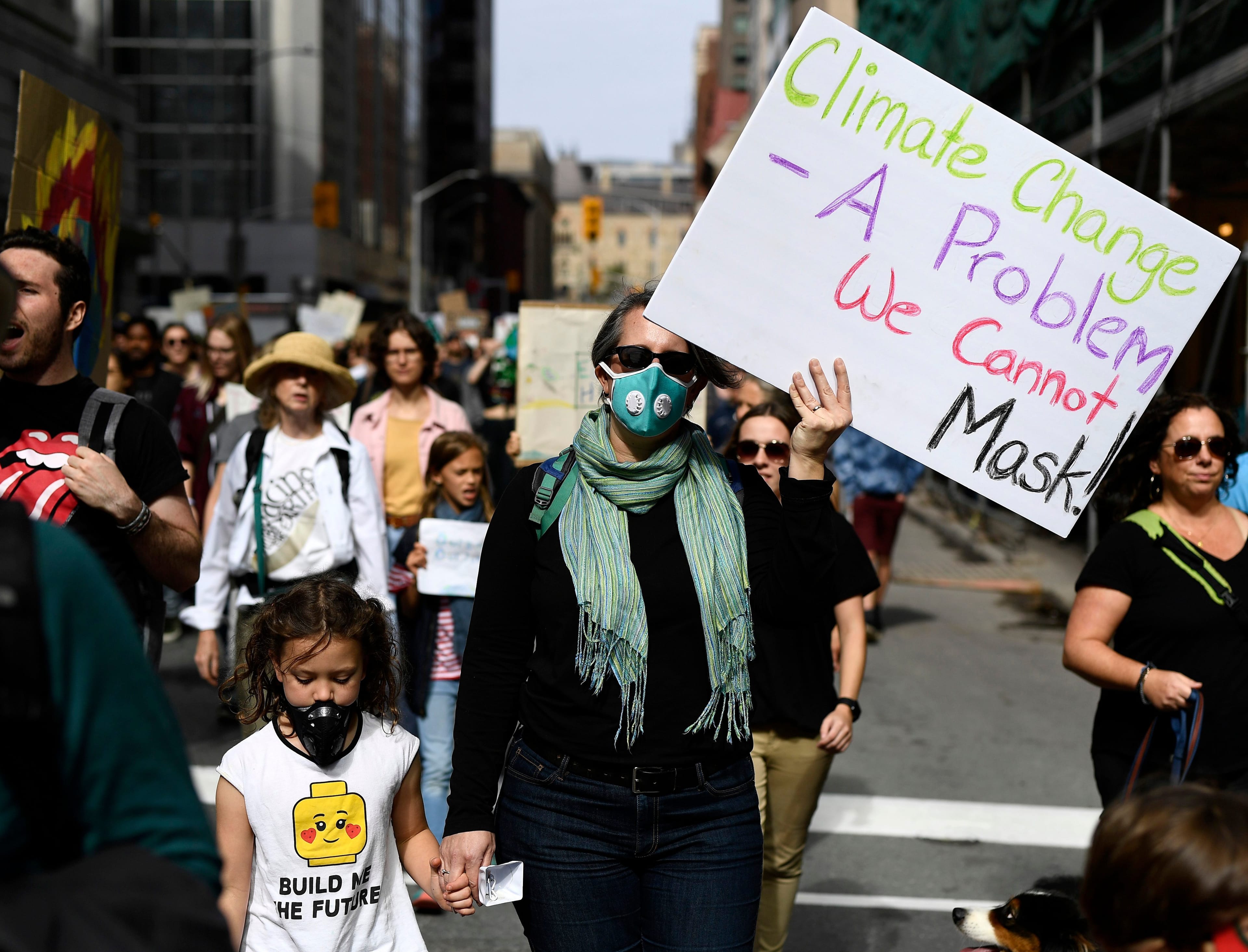 A woman and child wearing masks march in Ottawa as part of a Global Climate Strike, protesting against climate change and inaction, on Sept. 27, 2019. (Justin Tang/CP)