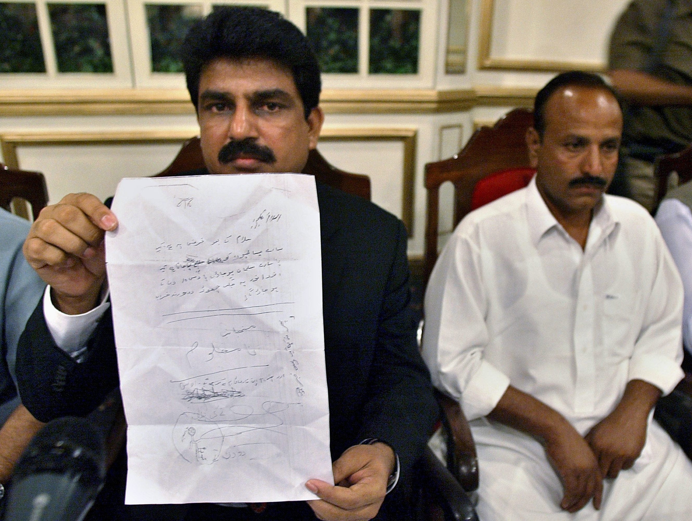 Shahbaz Bhatti, left, is seen in 2007 holding a threatening letter a Christian received in a pro-Taliban town where Pakistani Christians were ordered to convert to Islam (Anjum Naveed/AP)