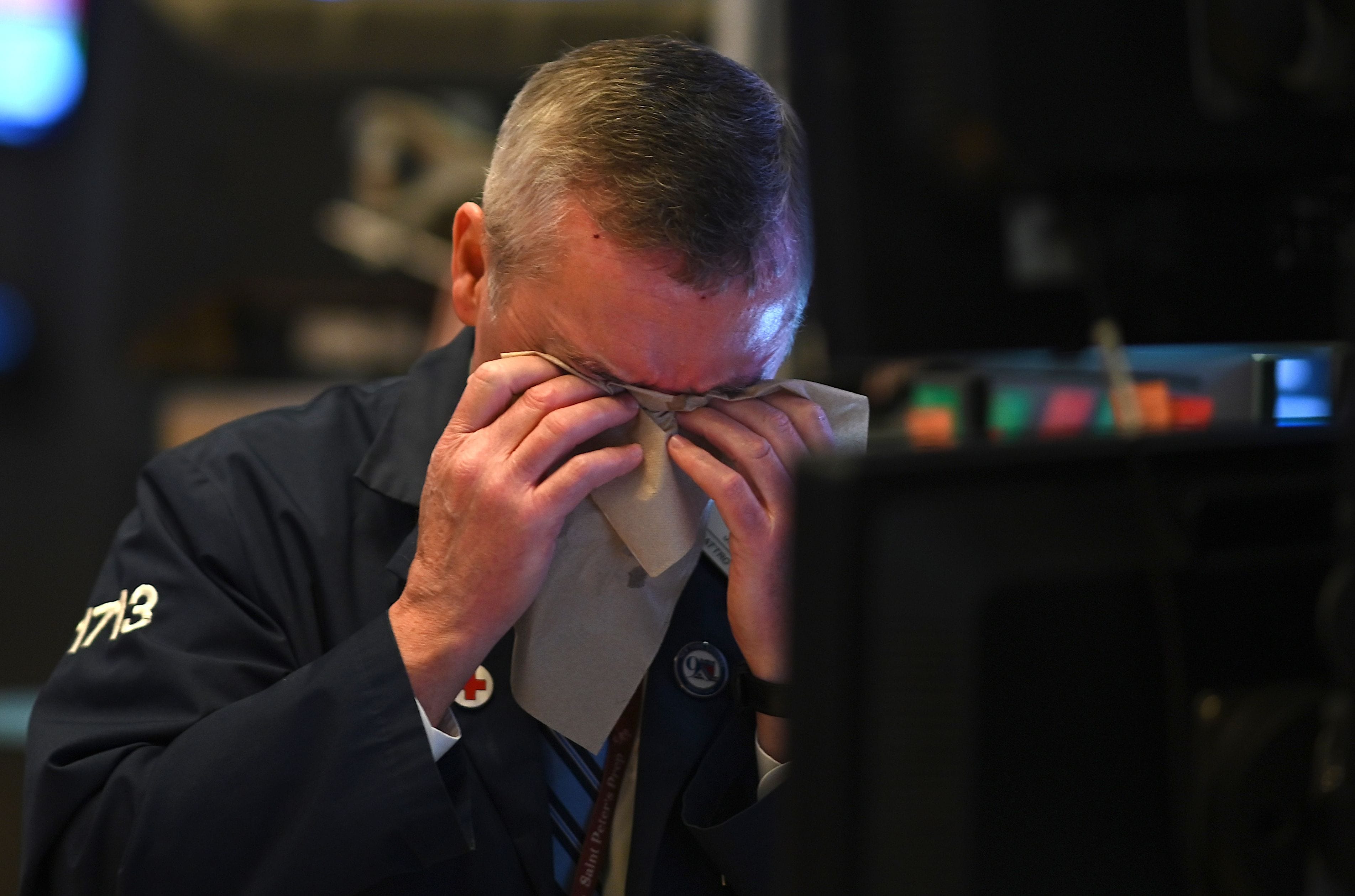 A trader wipes his face as he works during the closing bell at the New York Stock Exchange (NYSE) on March 3, 2020 on Wall Street in New York City. Fears of a global pandemic have hit global stock markets and left traders reeling. (Johannes Eisele/AFP via Getty Images)
