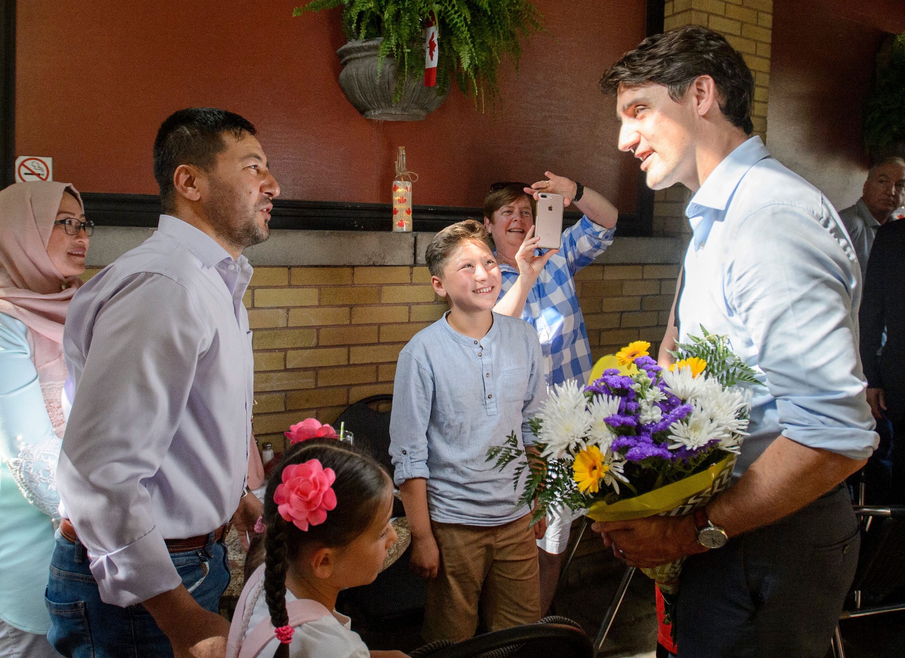 Canadian Prime Minister Justin Trudeau greets the Azimi family, who are refugees from Afghanistan after fleeing Syria, at the Old South Village Pub before having a meal in London, Ont. on Jul. 4, 2019. The Azimi family has been in Canada for 15 months. Refugees are among the highly vulnerable during the coronavirus pandemic. (Andrew Lahodynskyj/CP)