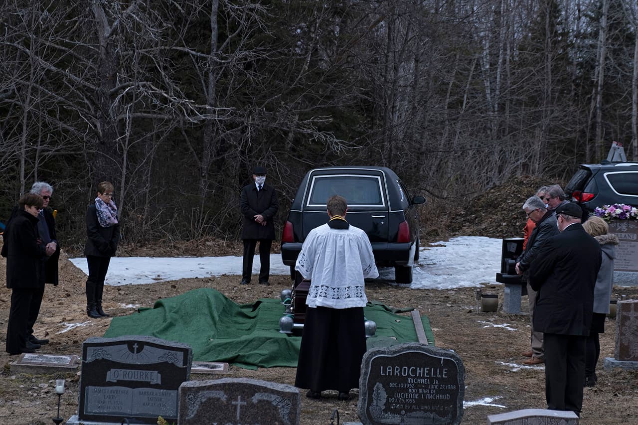 04/16/20 – Family members at the burial of their loved one standing six feet apart.