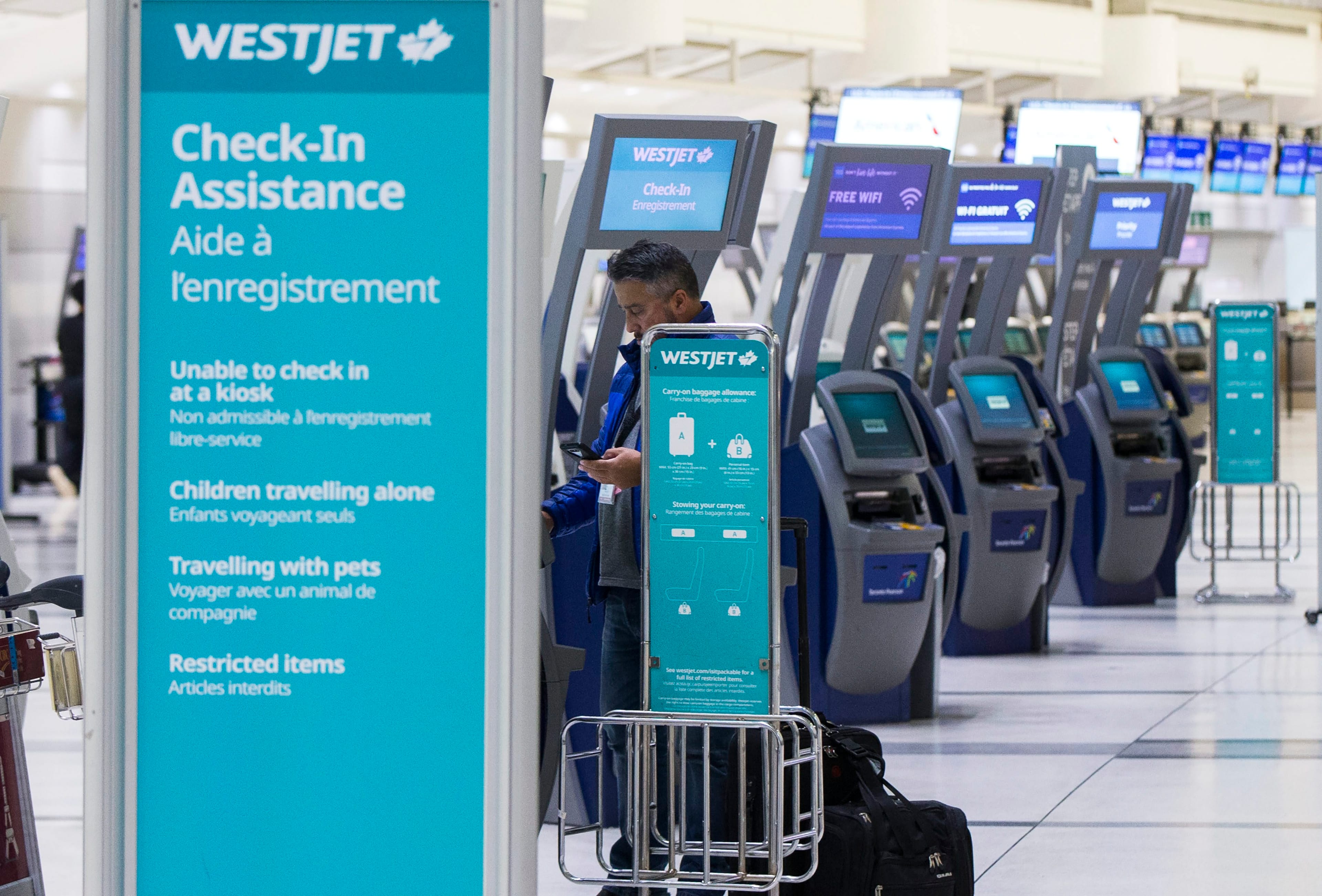 TORONTO, March 25, 2020 A traveller picks up boarding pass at the WestJet check-in express service area of Pearson International Airport in Toronto, Canada, March 24, 2020. (Zou Zheng/Xinhua via ZUMA Wire)