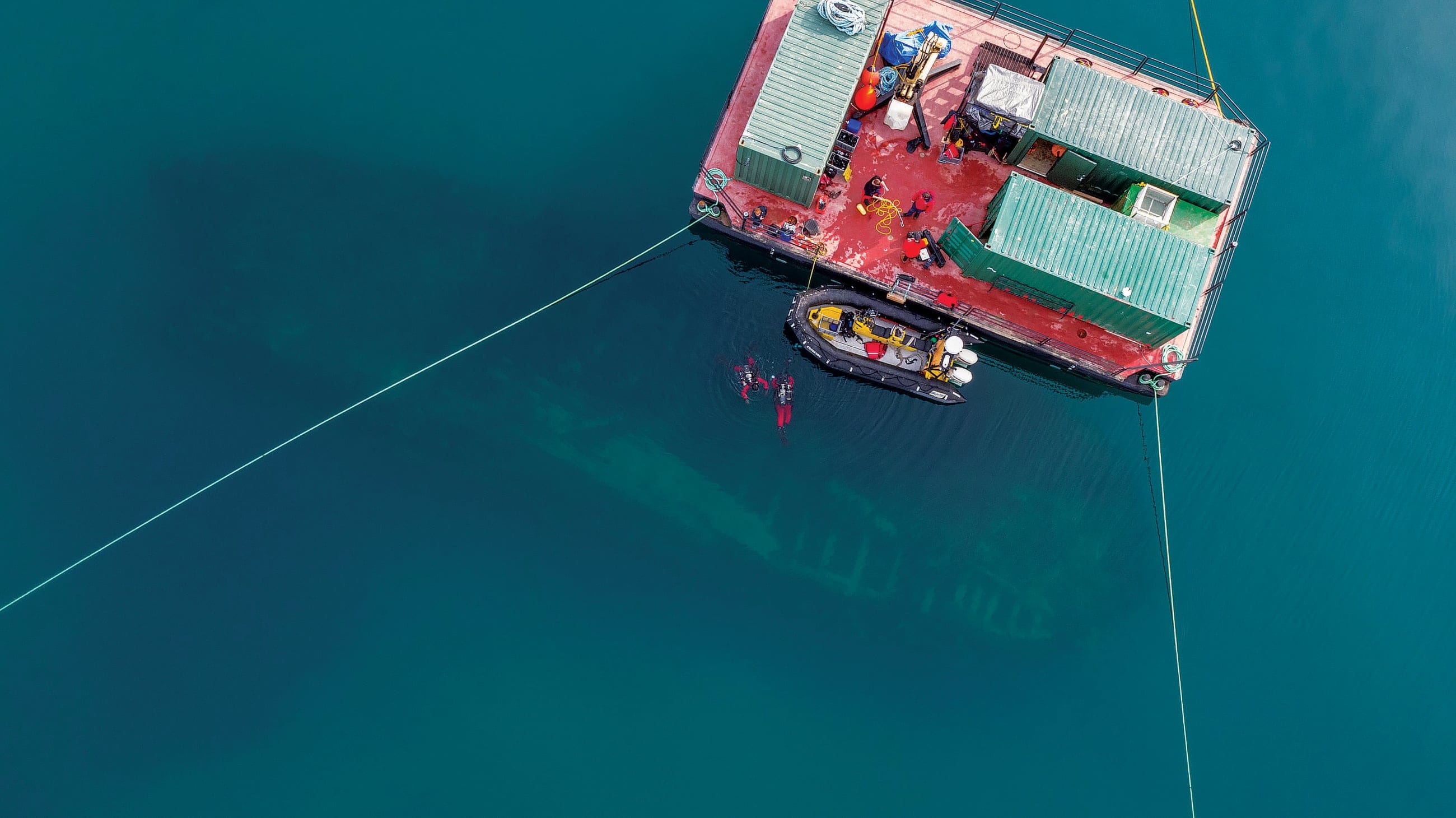 Qiniqtiryuaq (barge) above the Erebus site, wreck and divers visible.(Courtesy of Parks Canada)