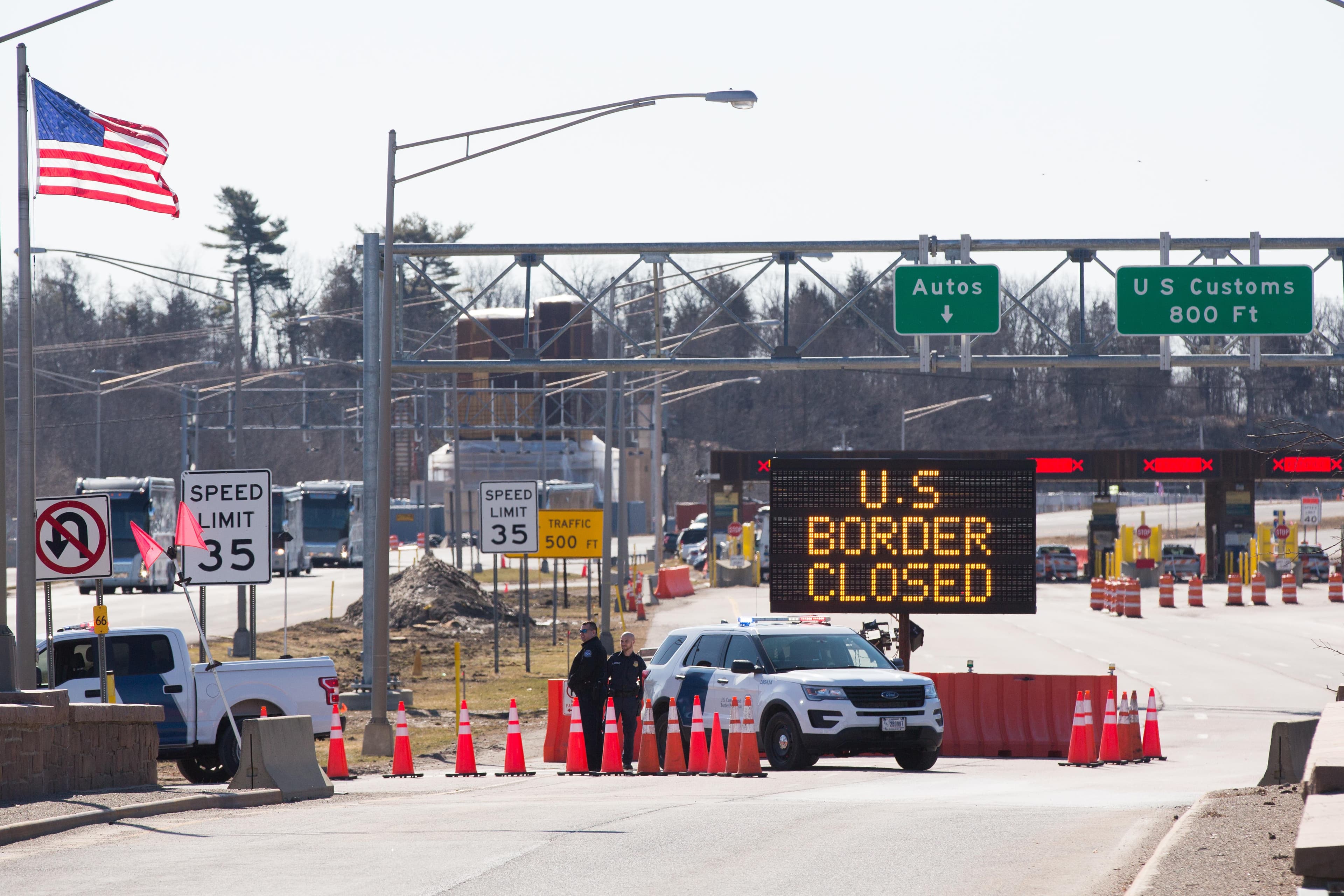 US Customs officers stand beside a sign saying that the US border is closed at the US/Canada border in Lansdowne, Ontario, on March 22, 2020. - The United States agreed with Mexico and Canada to restrict non-essential travel because of the coronavirus, COVID-19, outbreak and is planning to repatriate undocumented immigrants arriving from those countries. (Lars Hagberg /AFP/Getty Images)