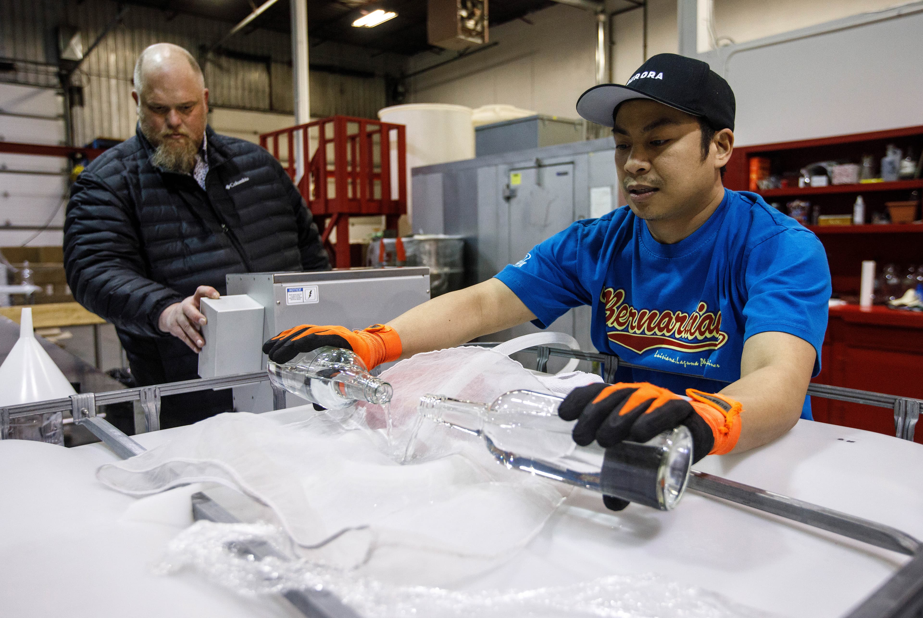 Red Cup Distillery owner de Groot (left) and an employee, Danilo Mendoza, making sanitizer (Photograph by Jason Franson)