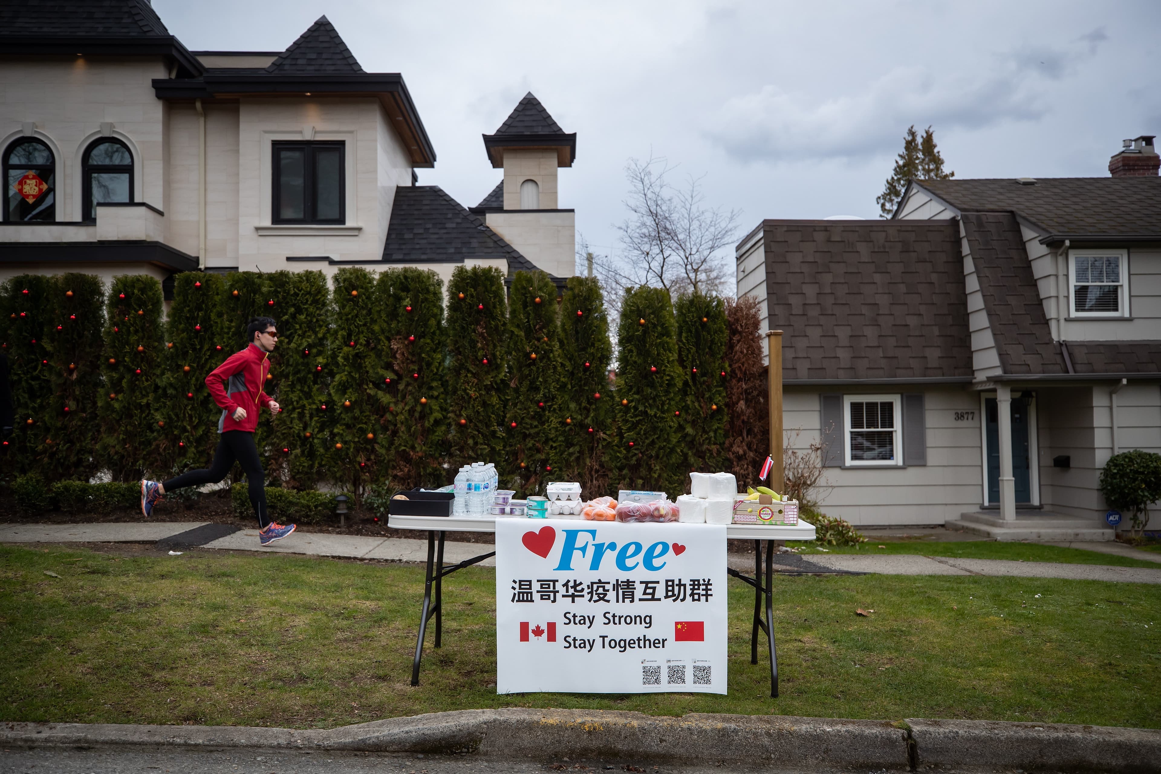 A man jogs past a table of free food and hygiene products left outside by a resident, in Vancouver, on Monday, March 23, 2020. (Darryl Dyck/CP)