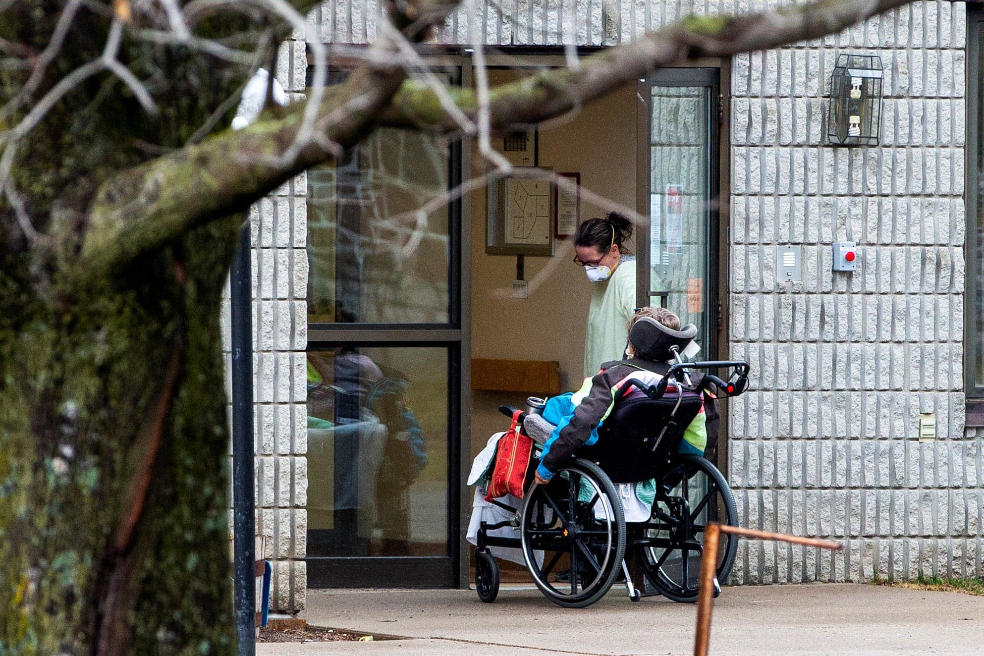 A woman opens the door to a person in a wheelchair at Pinecrest Nursing Home after several residents died and dozens of staff were sickened due to coronavirus disease (COVID-19), in Bobcaygeon, Ontario, Canada March 30, 2020. (Carlos Osorio/Reuters)