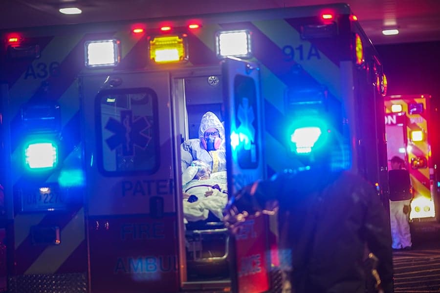 James Roy, left, and Brian Hirschmanner transported a P.U.I. (person under investigation for COVID-19) from Barnert Subacute Rehabilitation Center to a hospital in Paterson, N.J., on Tuesday, March 24, 2020. The emergency medical workers of Paterson, a poor, industrial city in the penumbra of pandemic-stricken New York, are working in a new, upside-down reality: Don't go in a home and don't touch the patient unless absolutely necessary. (Chang W. Lee/The New York Times/Redux)