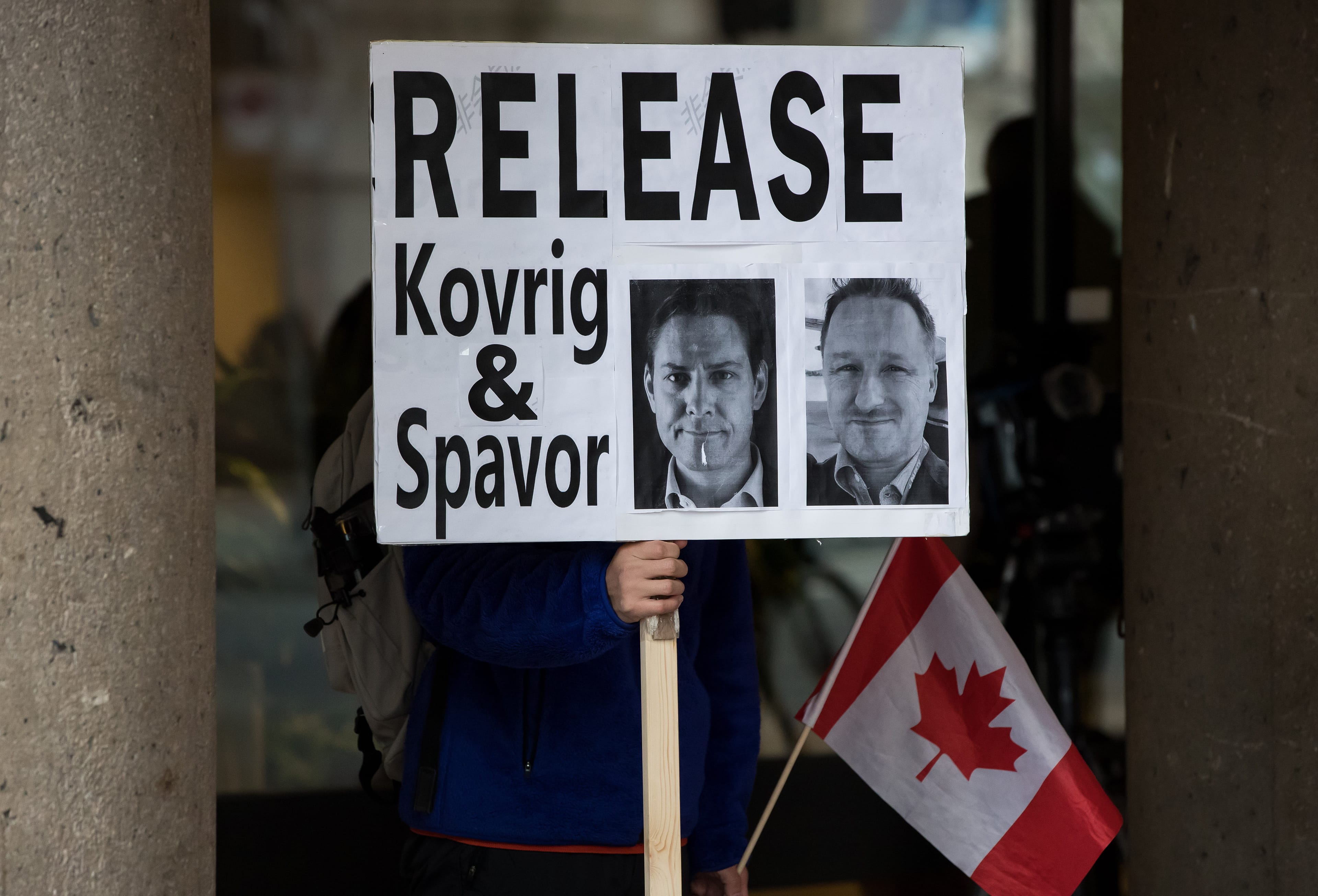 A man holds a sign bearing photographs of Kovrig and Spavor outside B.C. Supreme Court where Meng was attending a hearing in Vancouver on Jan. 21, 2020 (CP/Darryl Dyck)