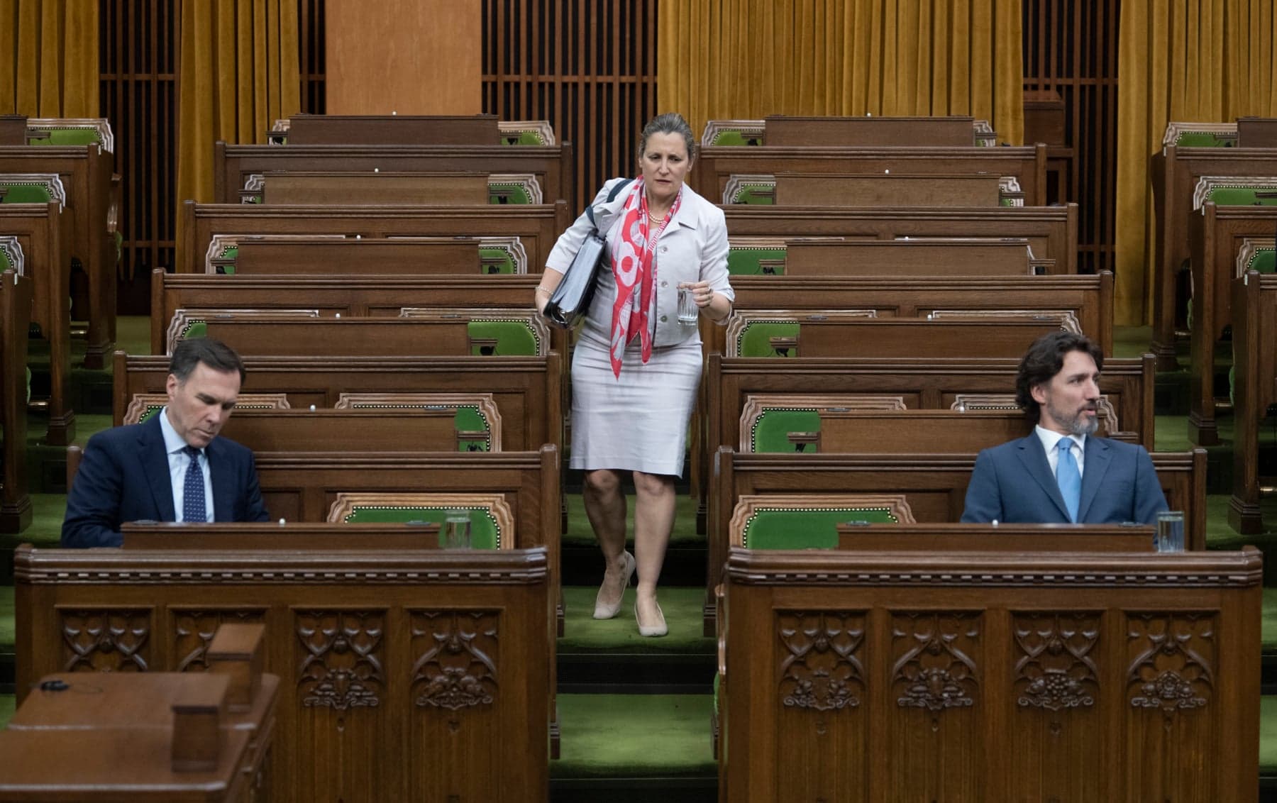 Deputy Prime Minister and Minister of Intergovernmental Affairs Chrystia Freeland looks for a seat as Minister of Finance Bill Morneaua and Prime Minister Justin Trudeau wait for a session of the Special Committee on the COVID-19 Pandemic to begin in the Chamber of the House of Commons in Ottawa, Wednesday May 13, 2020. (Adrian Wyld/CP)