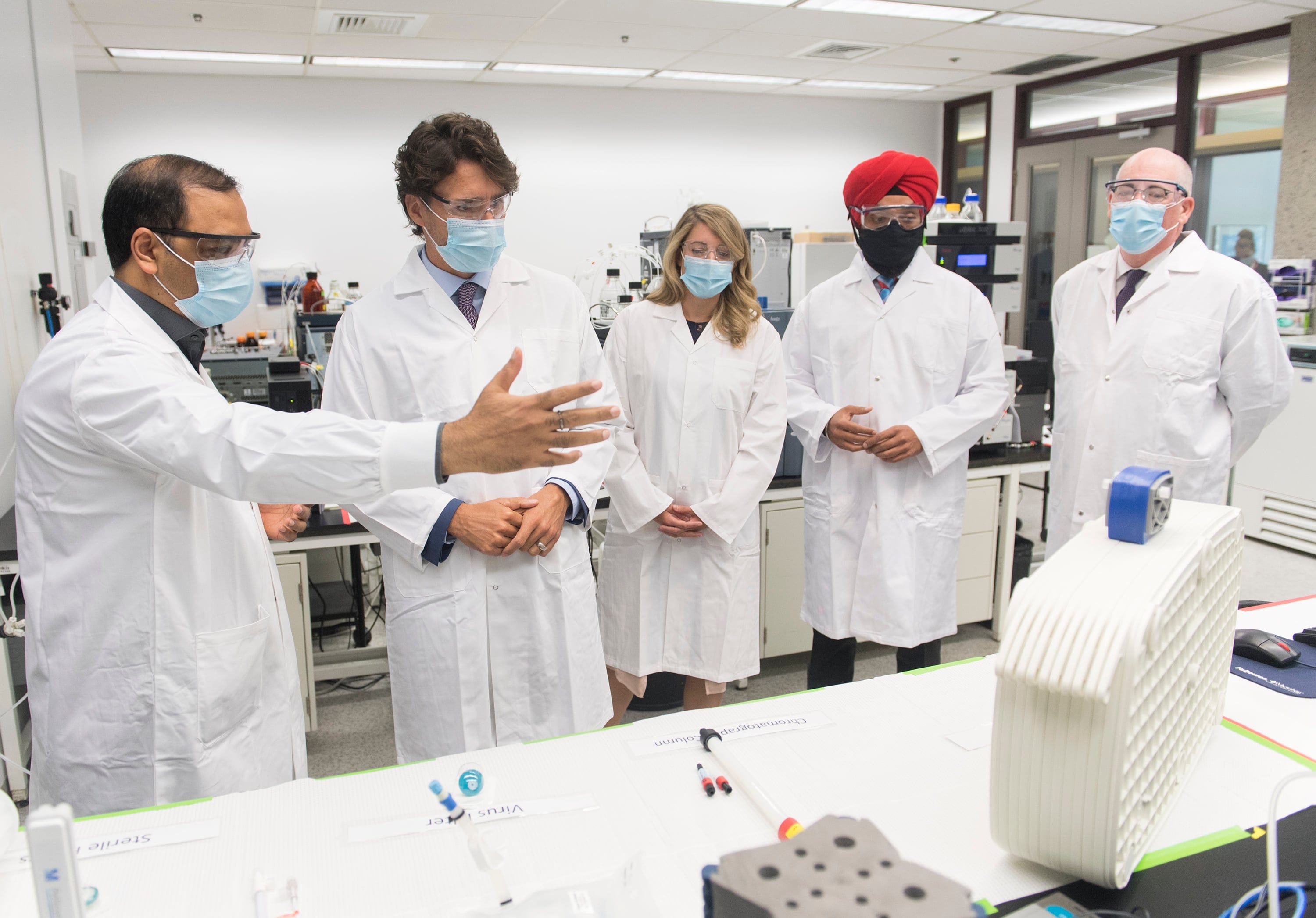 Prime Minister Justin Trudeau, second left, speaks with scientist Krishnaraj Tiwari, left, as Minister of Economic Development Melanie Joly, centre, Minister of Science and Industry Navdeep Bains and NRC President Iain Stewart, right, look on during a visit to the National Research Council of Canada (NRC) Royalmount Human Health Therapeutics Research Centre facility in Montreal, Monday, Aug 31, 2020. (Graham Hughes/CP)