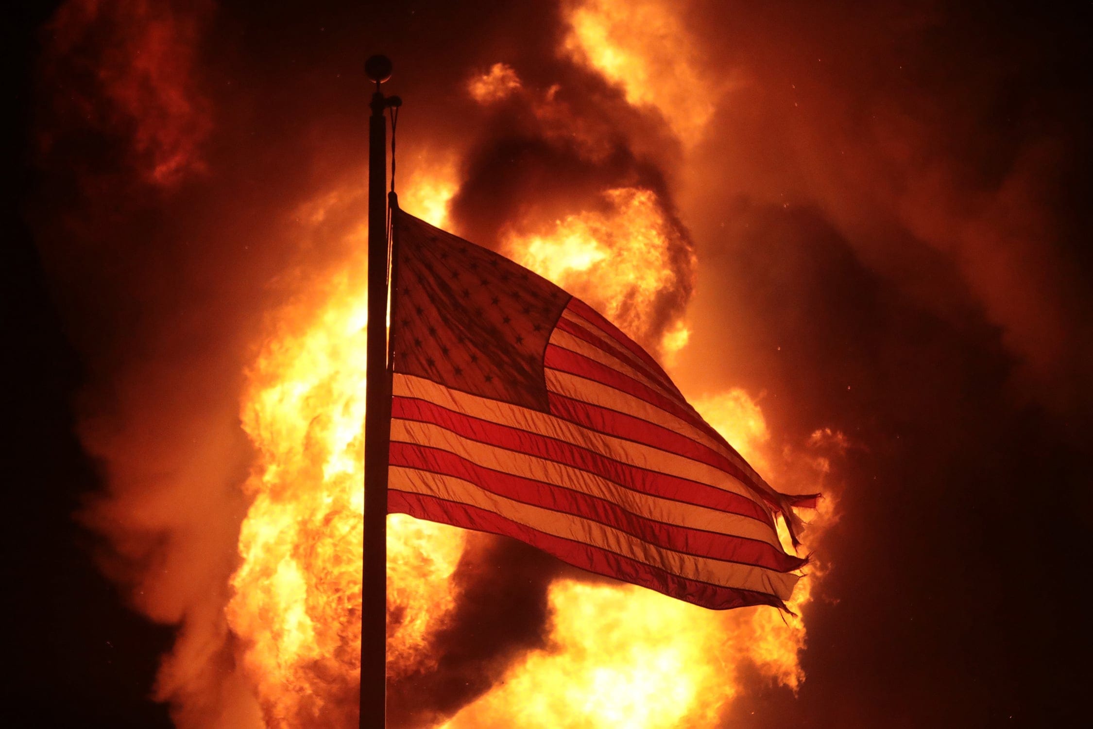 A flag flies outside a burning corrections building during protests and rioting in Kenosha, Wis. (Scott Olson/Getty Images)