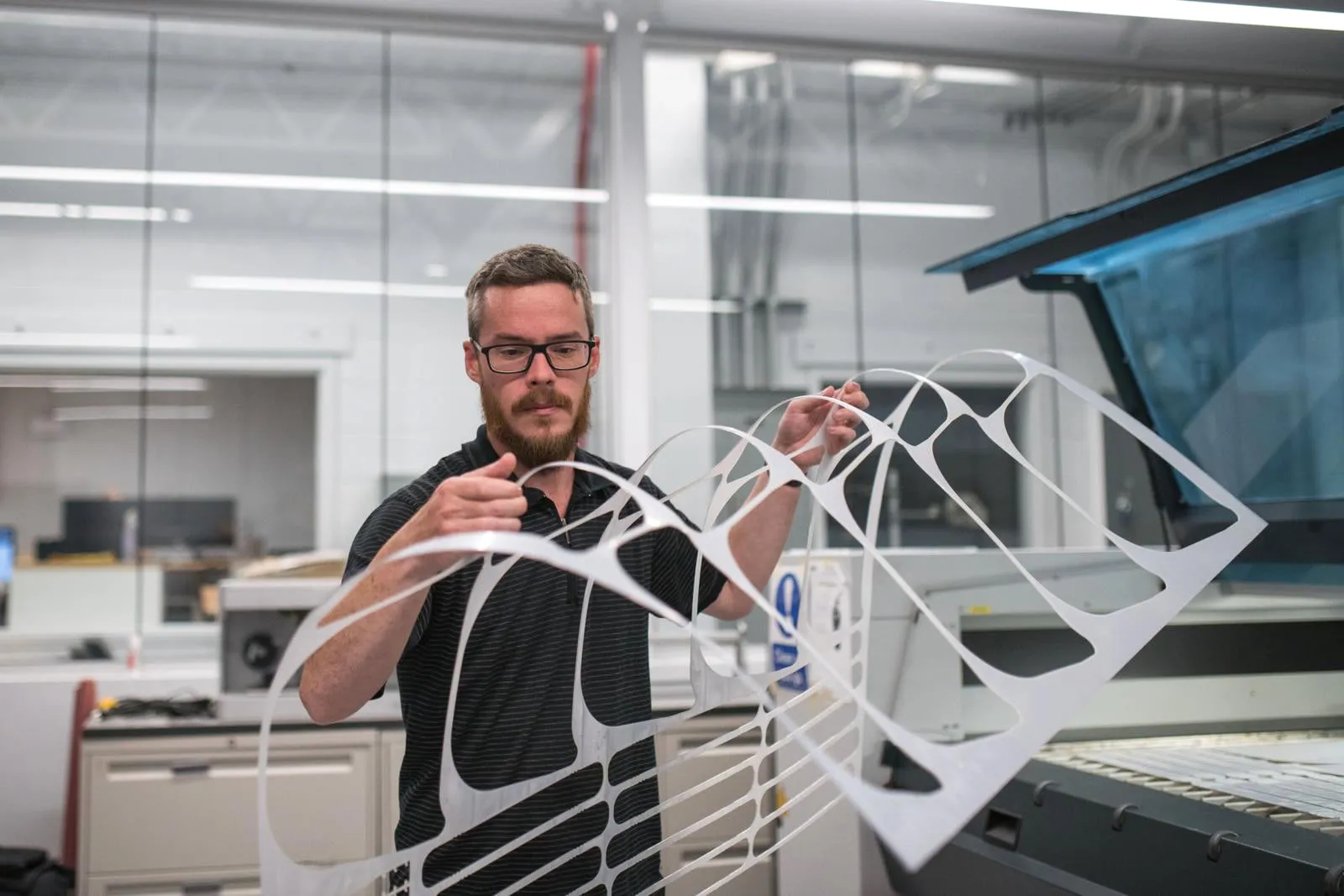 Matt Zeleny, an Applied Research Technologist, removes laser cut PPE face shields at the Camosun Innovates lab. (James MacDonald)