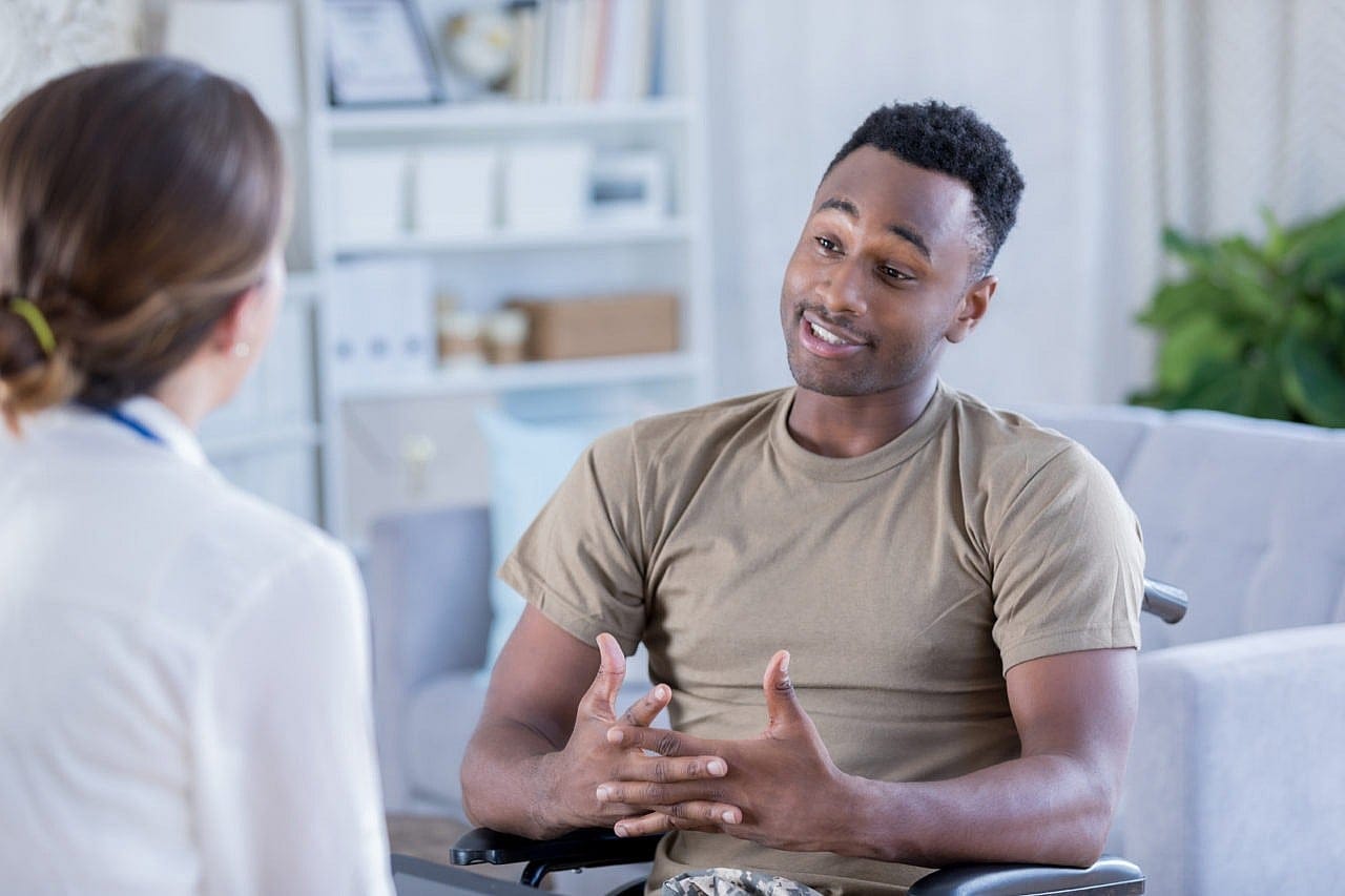 African American soldier in a wheelchair discusses problems with a female mental health professional.
