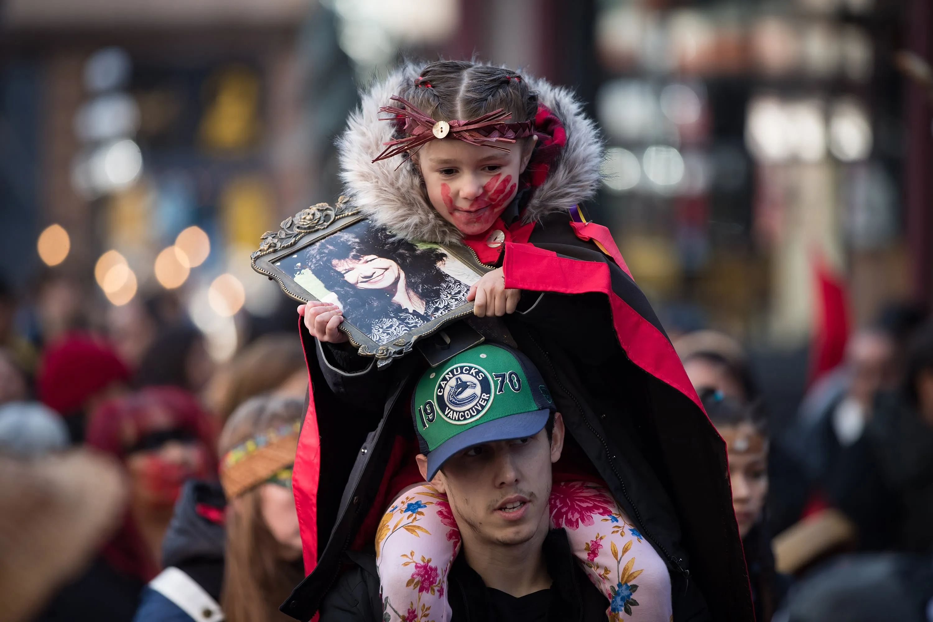Sofia Mitchell-Schiewe holds a photo of her late grandmother Francis Mitchell while sitting on her father James Schiewe's shoulders during the annual Women's Memorial March in Vancouver, on Feb. 14, 2020 (Darryl Dyck/CP)