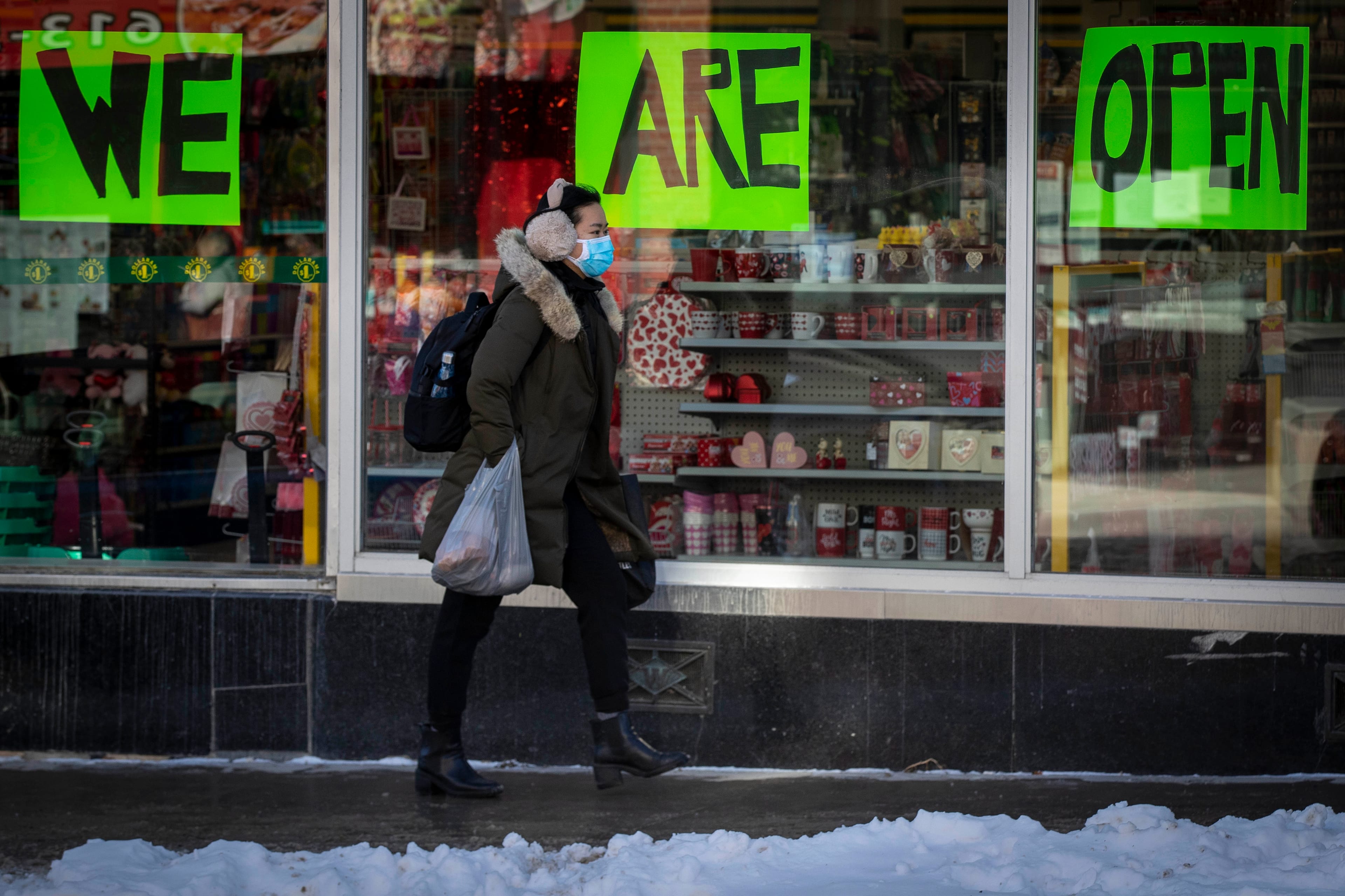 A person wears a mask to protect them from the COVID-19 virus while walking by an open store in Kingston, Ontario, on Wednesday Feb. 10, 2021. Kingston, Frontenac and Lennox & Addington (KFL&A) Public Health unit has moved into the green zone. THE CANADIAN PRESS/Lars Hagberg