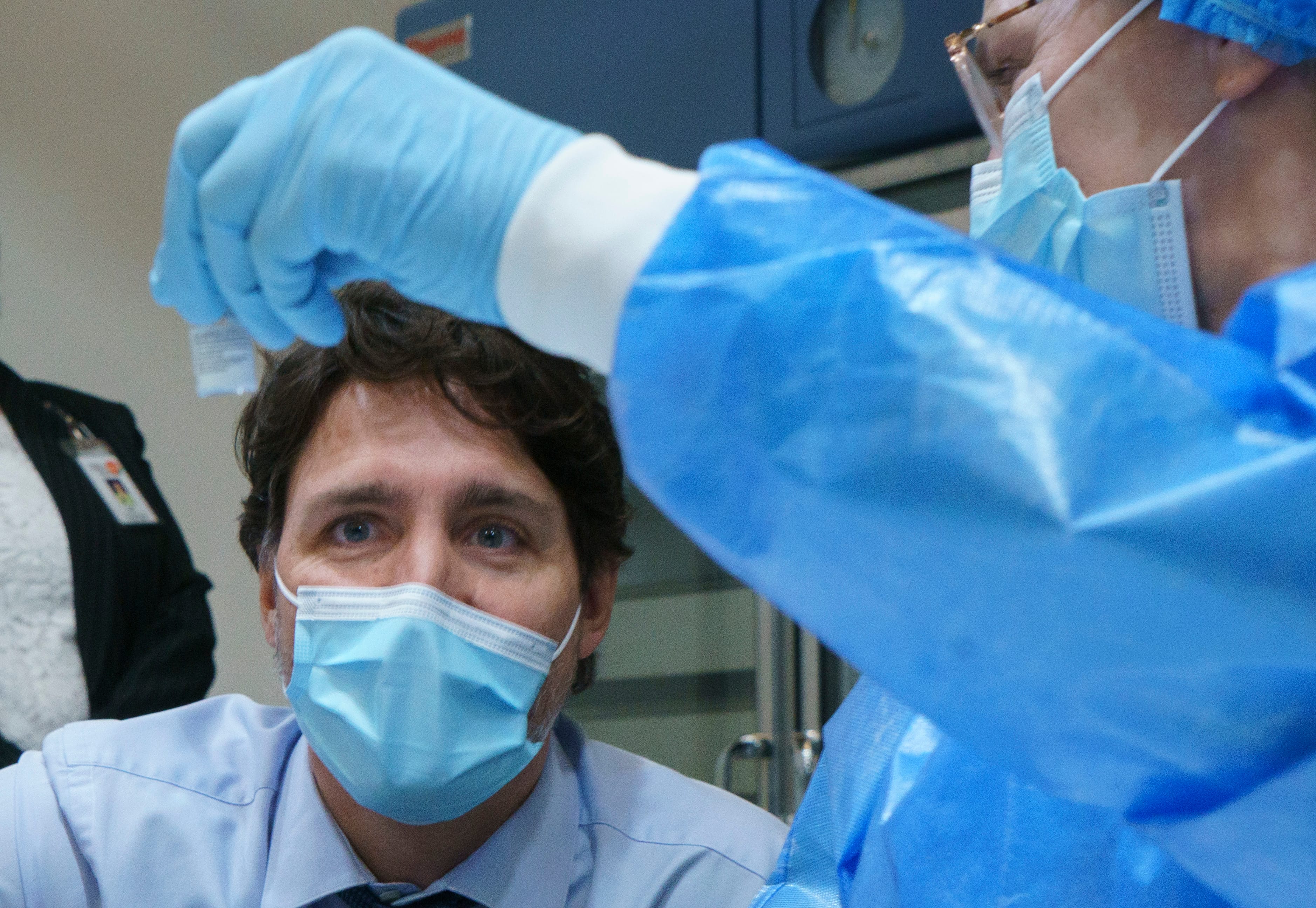 Trudeau looks at a COVID-19 vaccine vial as he tours a vaccination clinic in Montreal on March 15, 2021 (CP/Paul Chiasson)