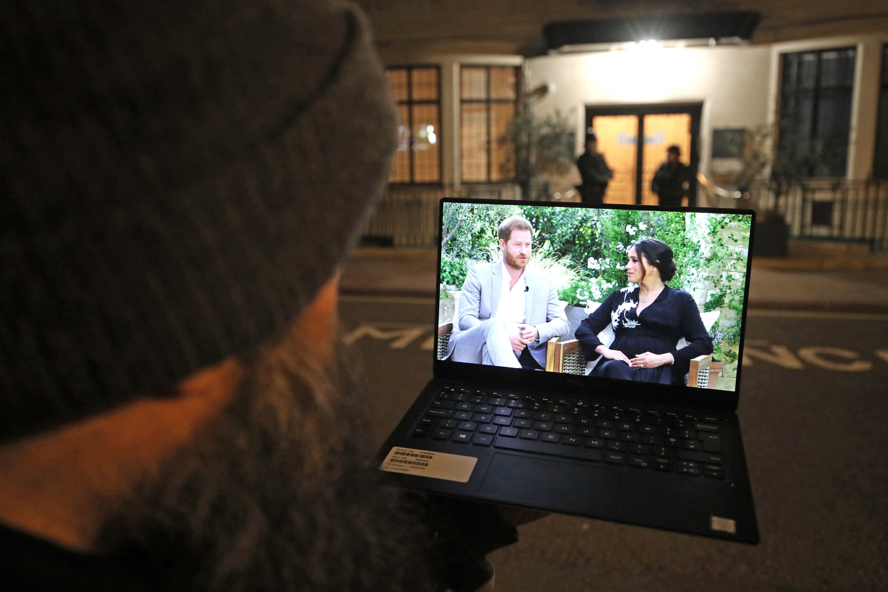 A man outside the hospital where Prince Philip, the Duke of Edinburgh, was being treated watches Oprah Winfrey's interview of Prince Harry and Meghan, the Duchess of Sussex. (Yui Mok/PA via AP)