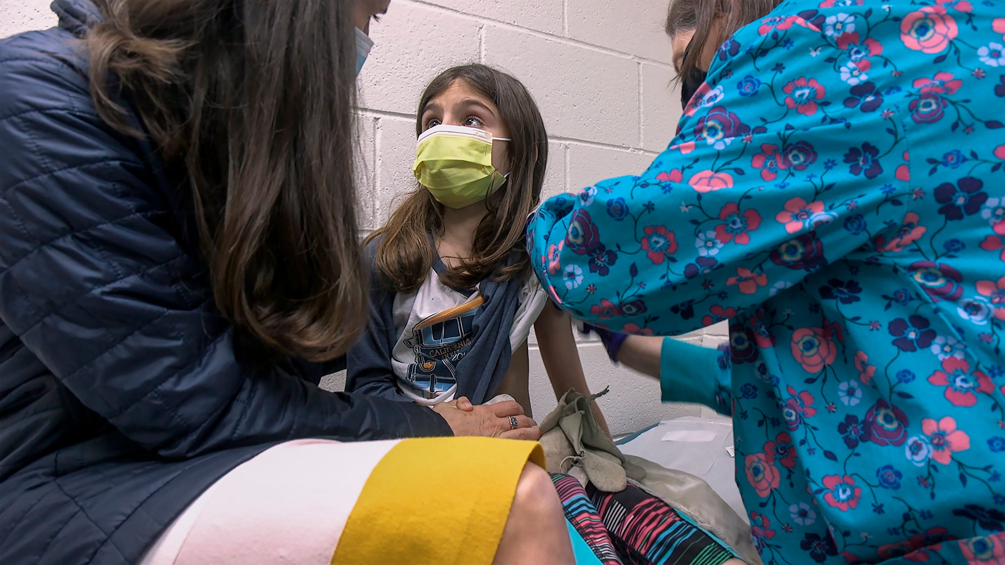 Alejandra Gerardo, 9, looks up to her mom, Dr. Susanna Naggie, as she gets the first of two Pfizer COVID-19 vaccinations during a clinical trial for children at Duke Health in Durham, N.C. (Shawn Rocco/Duke Health via AP)