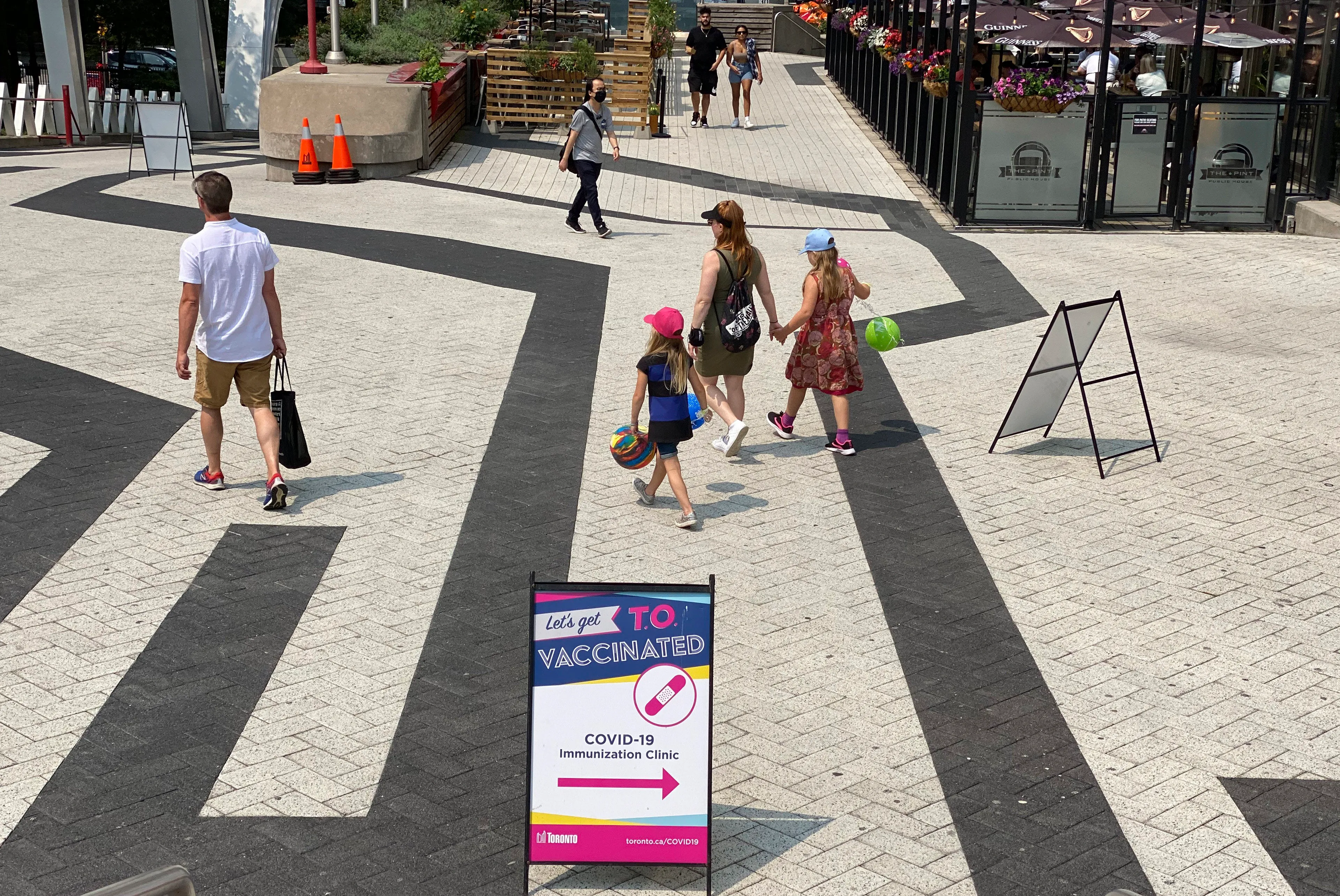 People pass by the sign of a COVID-19 immunization clinic in downtown Toronto, Canada, on Sunday, July 18, 2021. (Kamran Jebreili/AP/CP)