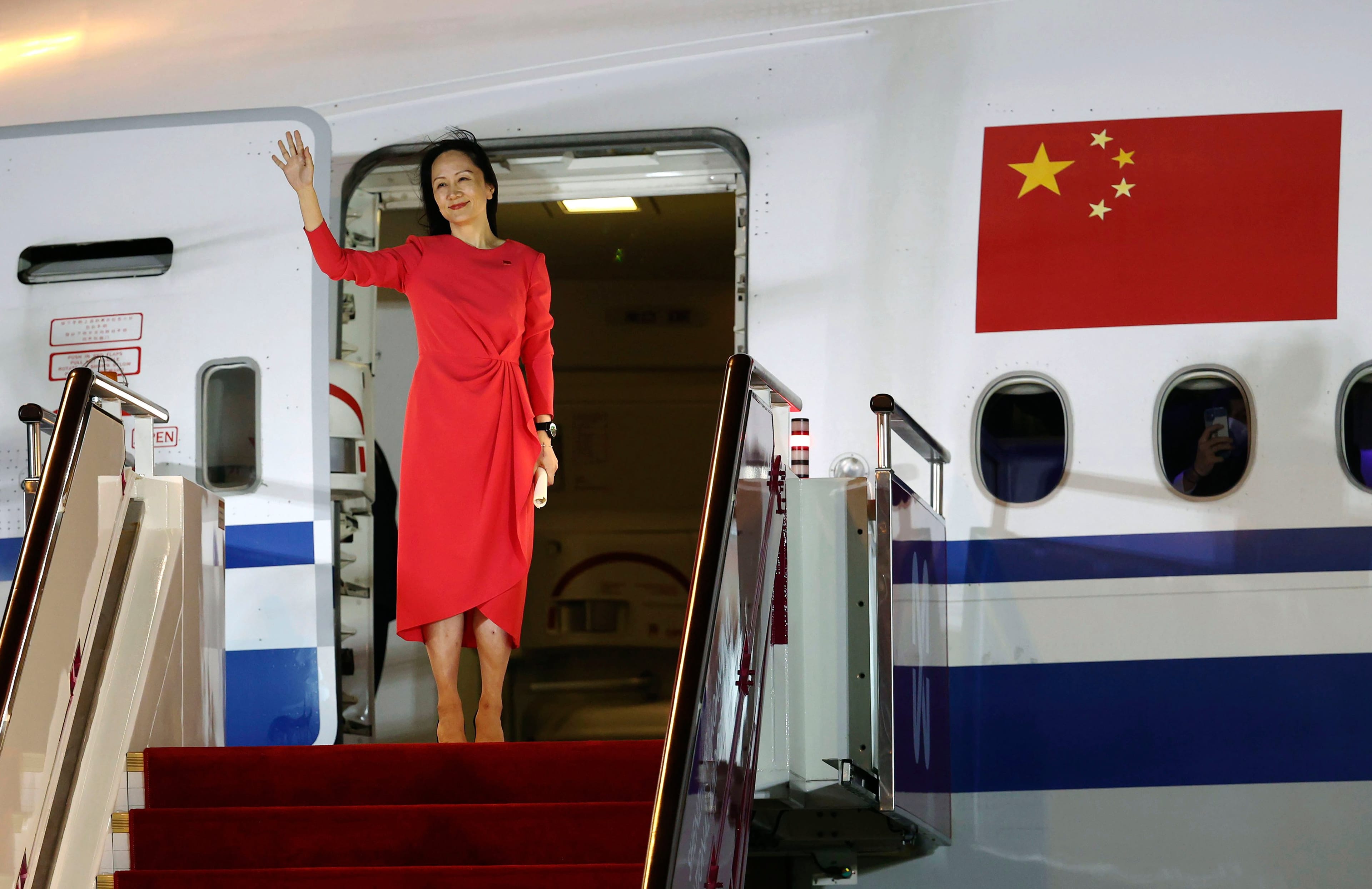 In this photo released by China's Xinhua News Agency, Huawei CFO Meng Wanzhou waves as she steps out of an airplane after arriving at Shenzhen Bao'an International Airport in Shenzhen, China. (Jin Liwang/Xinhua via AP)