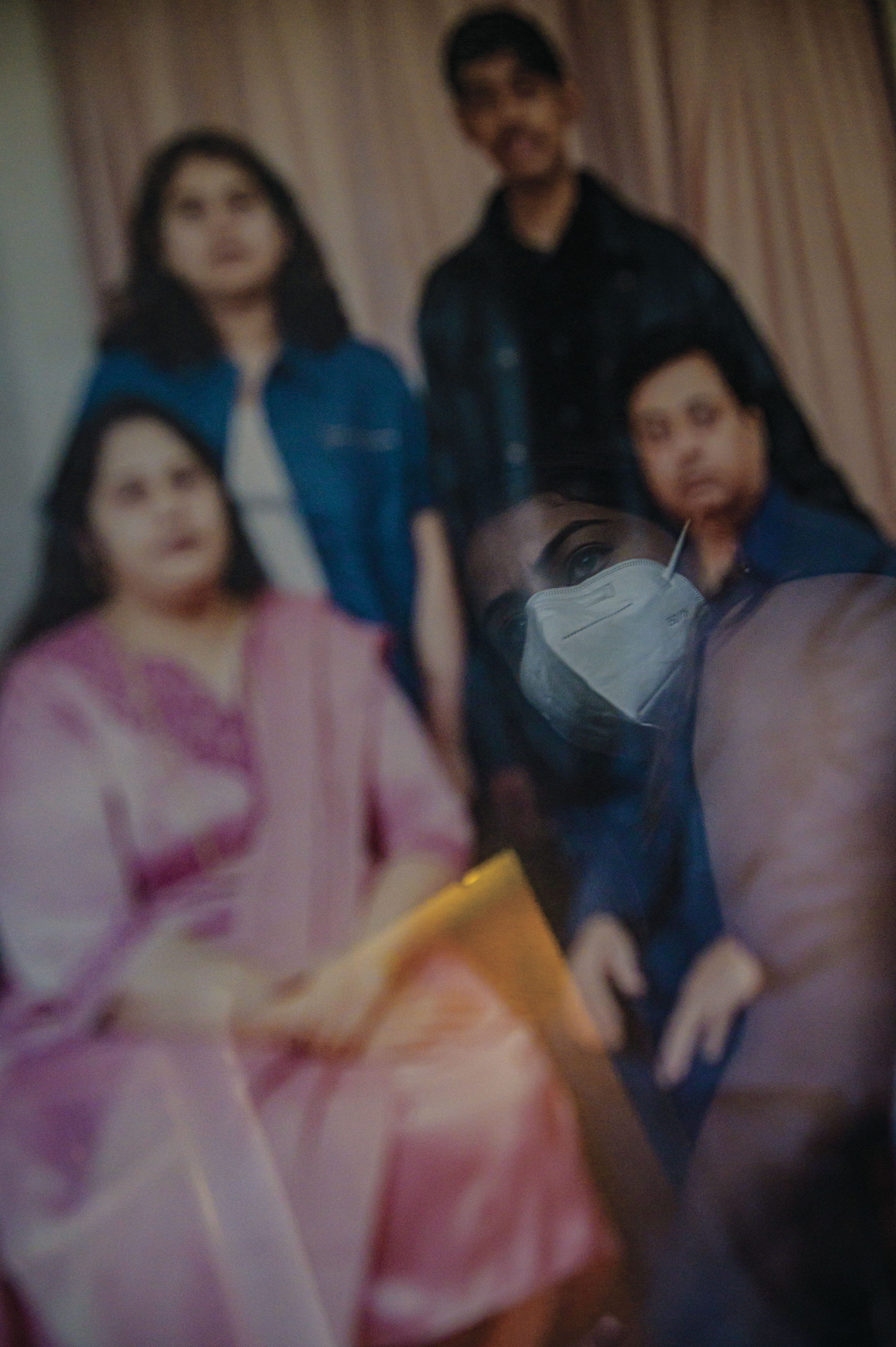 Menka, reflected in a portrait with her parents and brother; she lost all three to COVID in March. (Photograph by Christopher Katsarov Luna)
