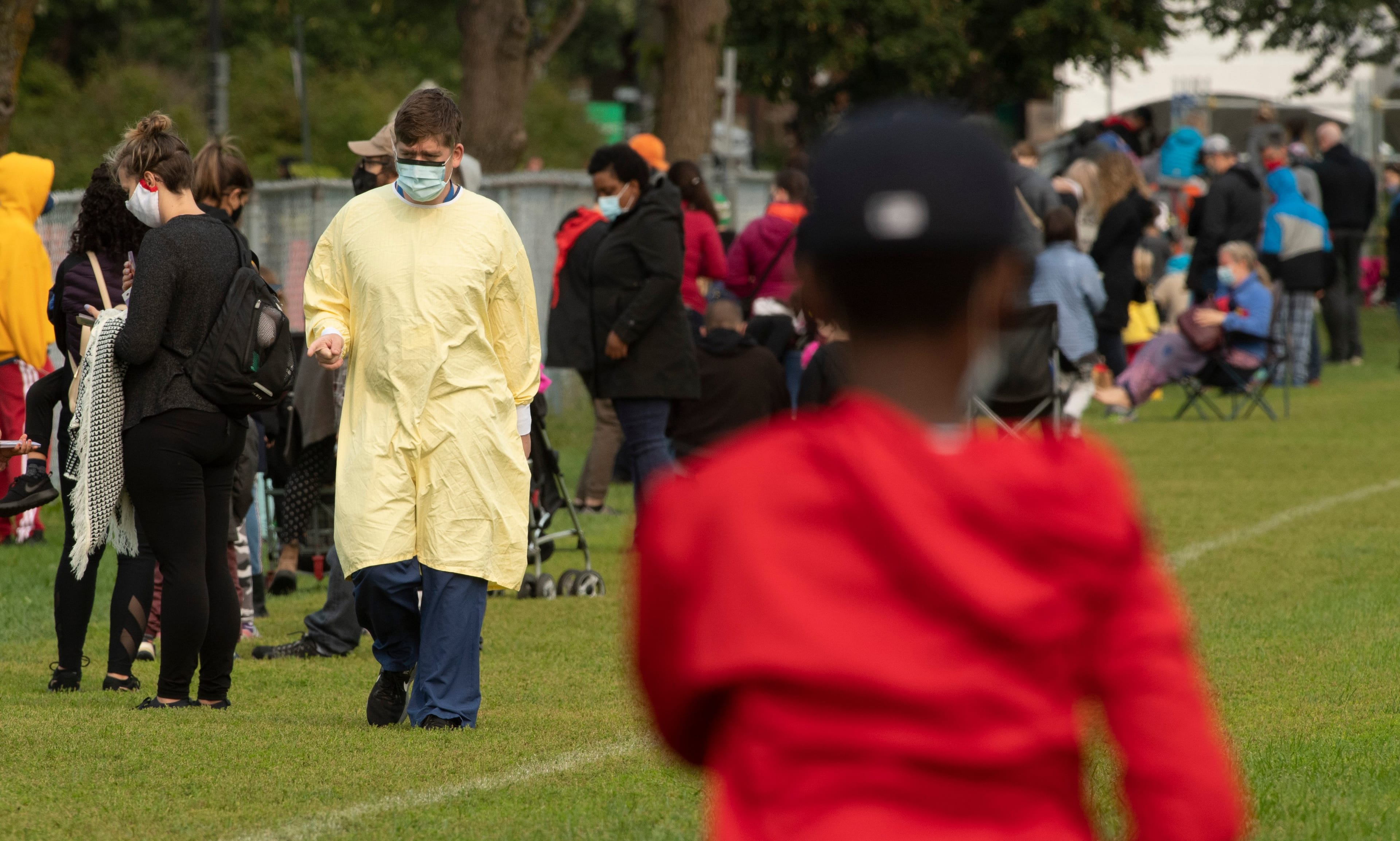 A health-care work walks along the line up of people waiting outside a COVID testing facility in Ottawa, on Sept. 15, 2020 (Adrian Wyld/CP)