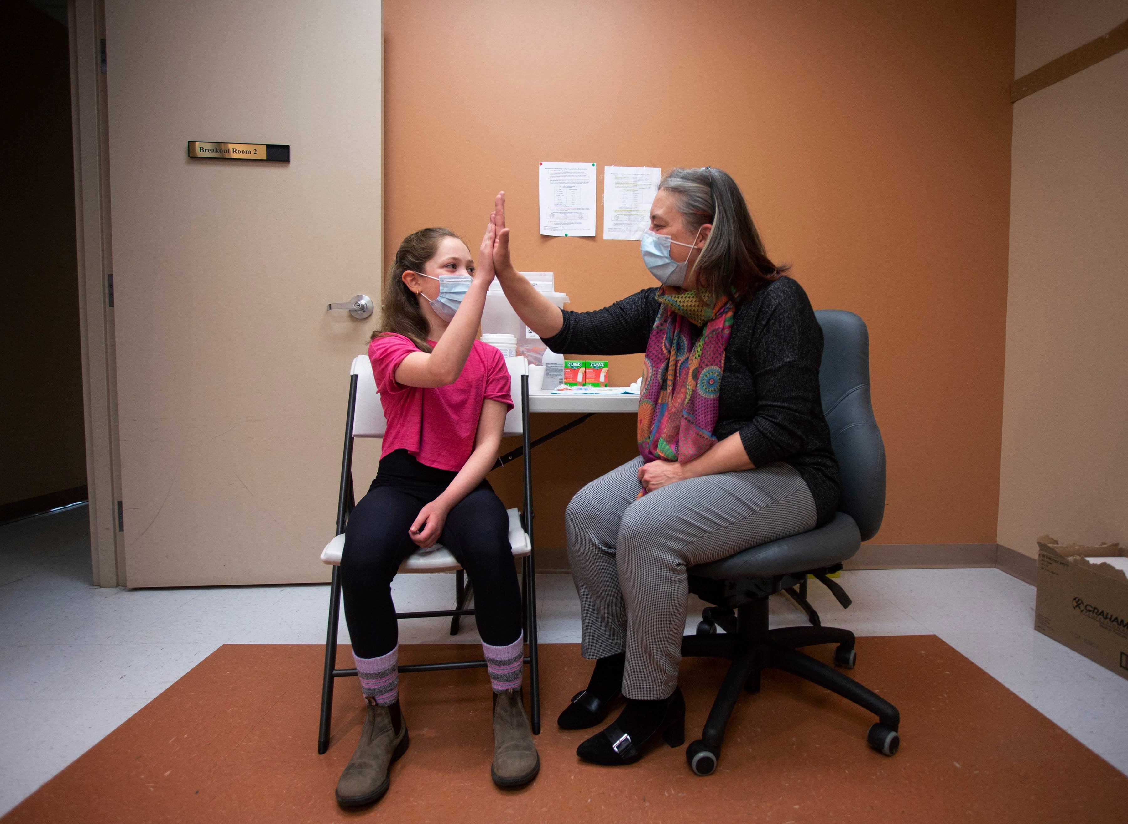 Dr. Janice Fitgerald, Chief Medical Officer of Health receives a high-five from 11 year old Keira O'Keefe following administering her a COVID-19 vaccine in St. John's N.L., today, Thursday, November 25, 2021. THE CANADIAN PRESS/Paul Daly