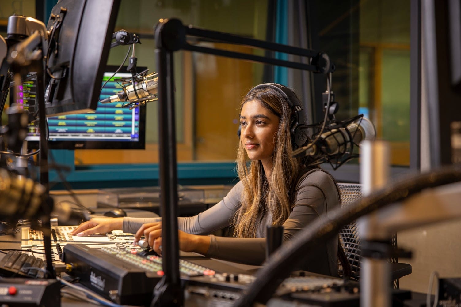 Woman in a recording room looking at a computer with hands on a keyboard