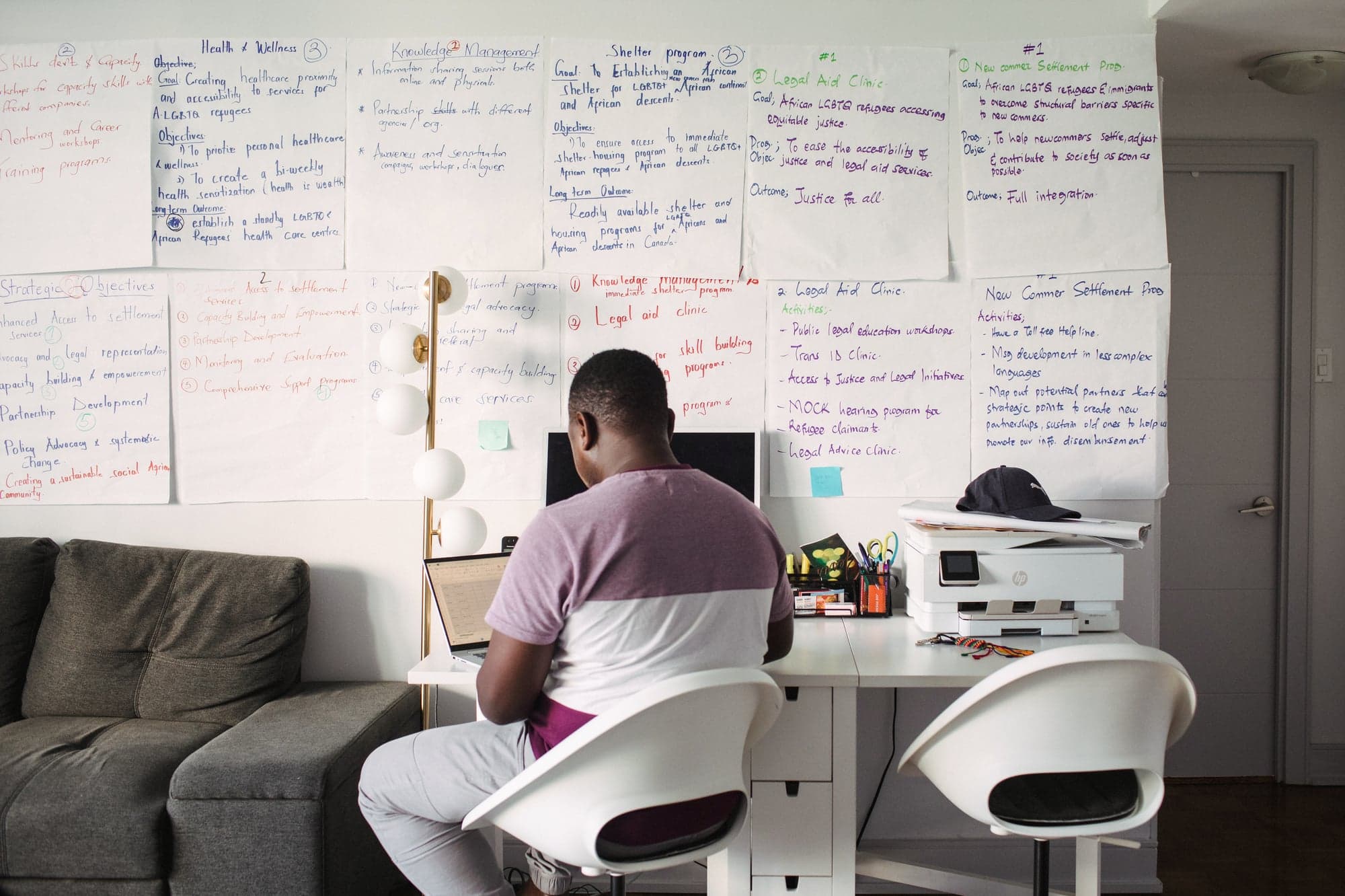 A man in a purple and white shirt sits at a desk