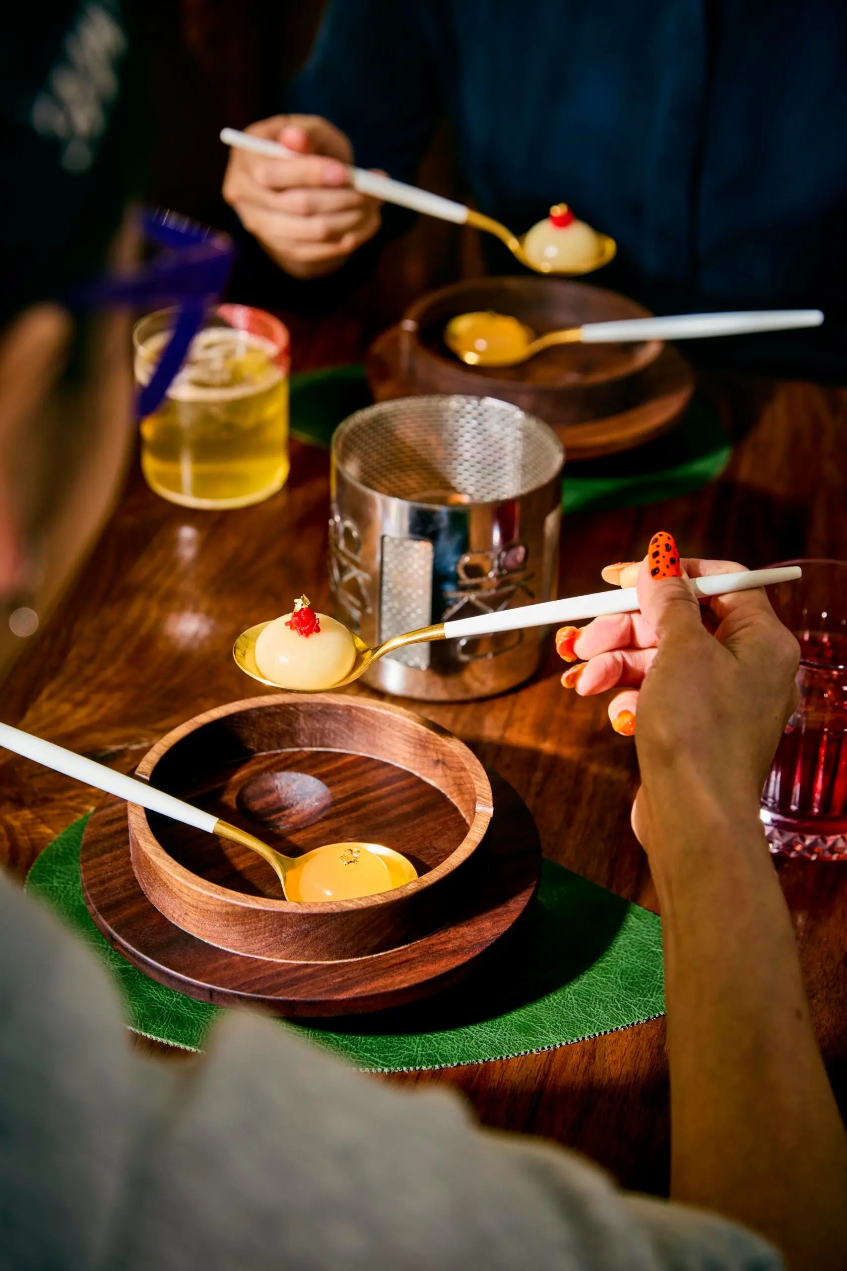 Hands scooping one-bite spheres from a table set with wooden dishes
