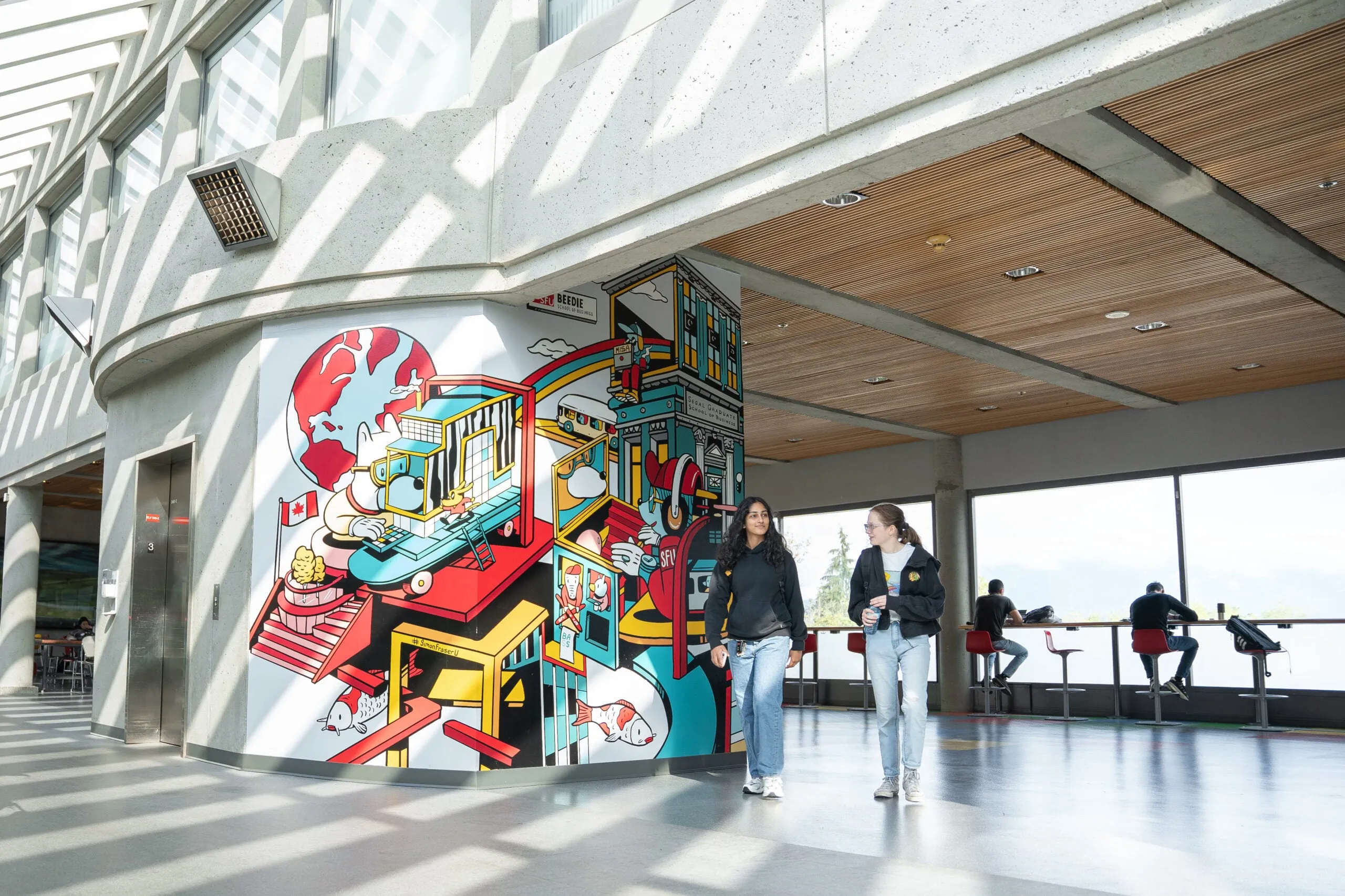 Two students walking past a mural