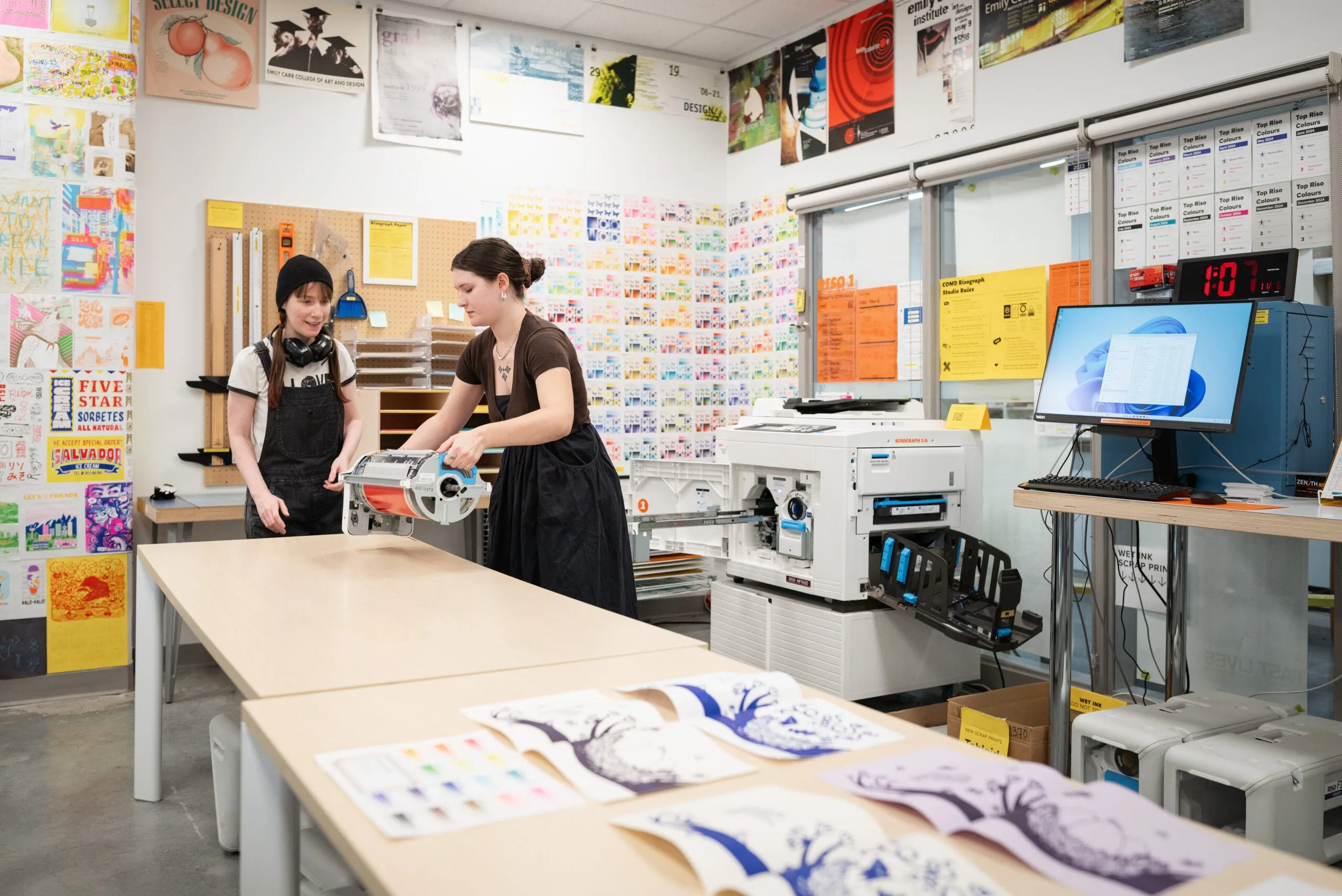 Two students in a classroom, working on printed art pieces
