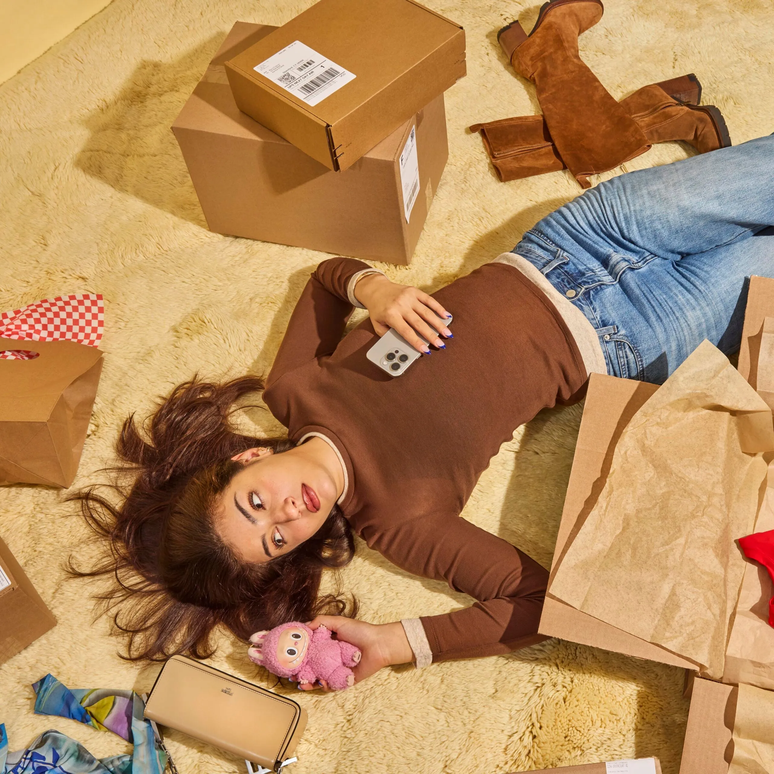 A young woman laying down on a beige carpet, surrounded by numerous online order packages